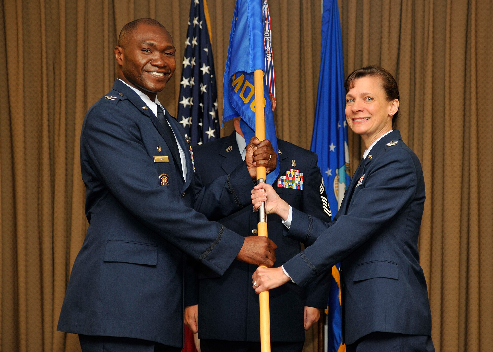 Col. Rodney Lewis, 319th Air Base Wing commander, hands the 319th Medical Group guidon to Col. Therese Bohusch, the new 319th MDG commander, during a change of command ceremony on Grand Forks Air Force Base, N.D., July 24, 2015. Bohusch assumed command from Col. Terri Bailey. (U.S. Air Force photo by Senior Airman Xavier Navarro/released)
