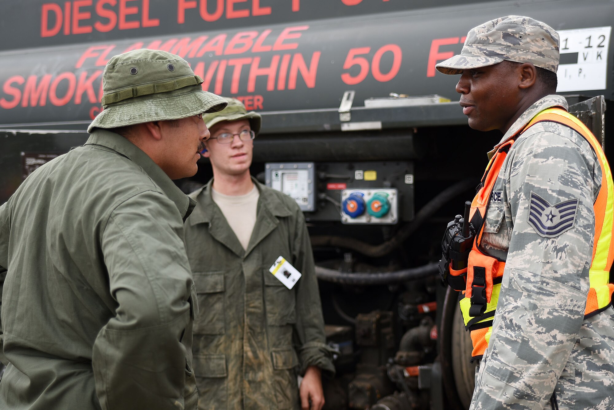 Technical Sgt. Shaderak Aigbekaen (right), 421st Combat Training Squadron, who acts as a Ground Safety Manager during Exercise Turbo Distribution 15-7, ensures that petroleum delivery participants Staff Sgt. Paul Olmos(left) and Airman First Class Chase Madeen(center), 87th Logistics Reasdiness Squadron have the proper personnel protective equipment for handling equipment at Joint Base McGuire-Dix-Lakehurst, New Jersey, on July 21, 2015. The 87th LRS team acts as host nation fuels specialists during the exercise and refuels all vehicles, equipment and generators used by the participants. TD 15-7, a Joint Task Force-Port Opening field training exercise hosted by the U.S. Air Force Expeditionary Center at Joint Base McGuire-Dix-Lakehurst, New Jersey, tests the ability to rapidly deploy and employ a JTF-PO Aerial Port of Debarkation enabling capability in direct support to a regional combatant command. (U.S. Air Force photo/Danielle Brooks)