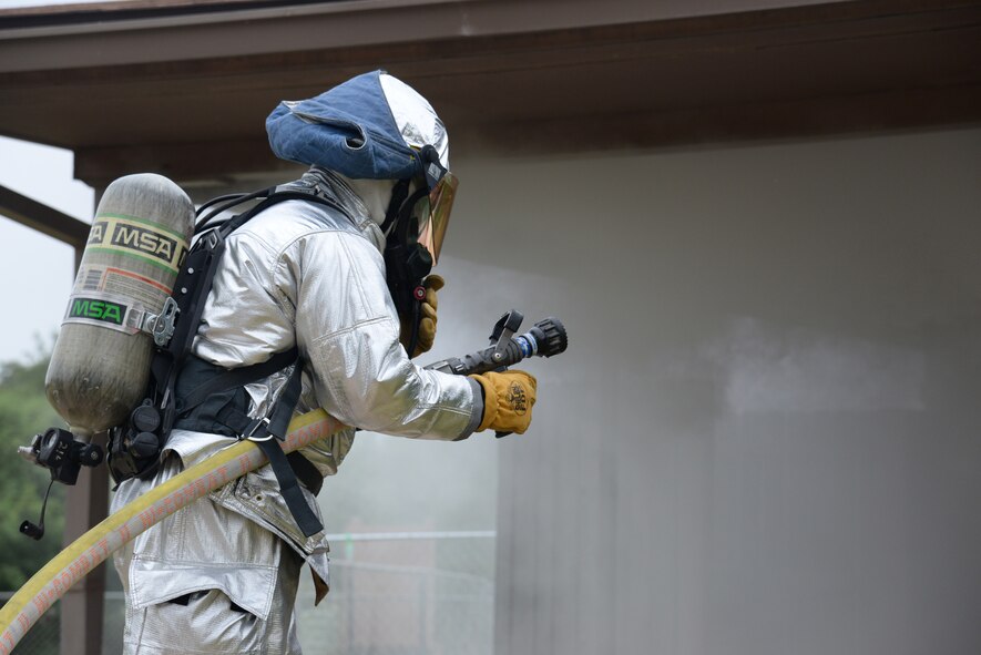 A Laughlin 47th Civil Engineer Squadron firefighter stays ready to enter a base home during a structural training exercise on Laughlin Air Force Base, Texas, July 22, 2015. The firefighter is part of the rapid intervention team during the exercise, and it's their job to respond with support if something goes wrong inside the home. (U.S. Air Force photo by Airman 1st Class Brandon May) (Released)