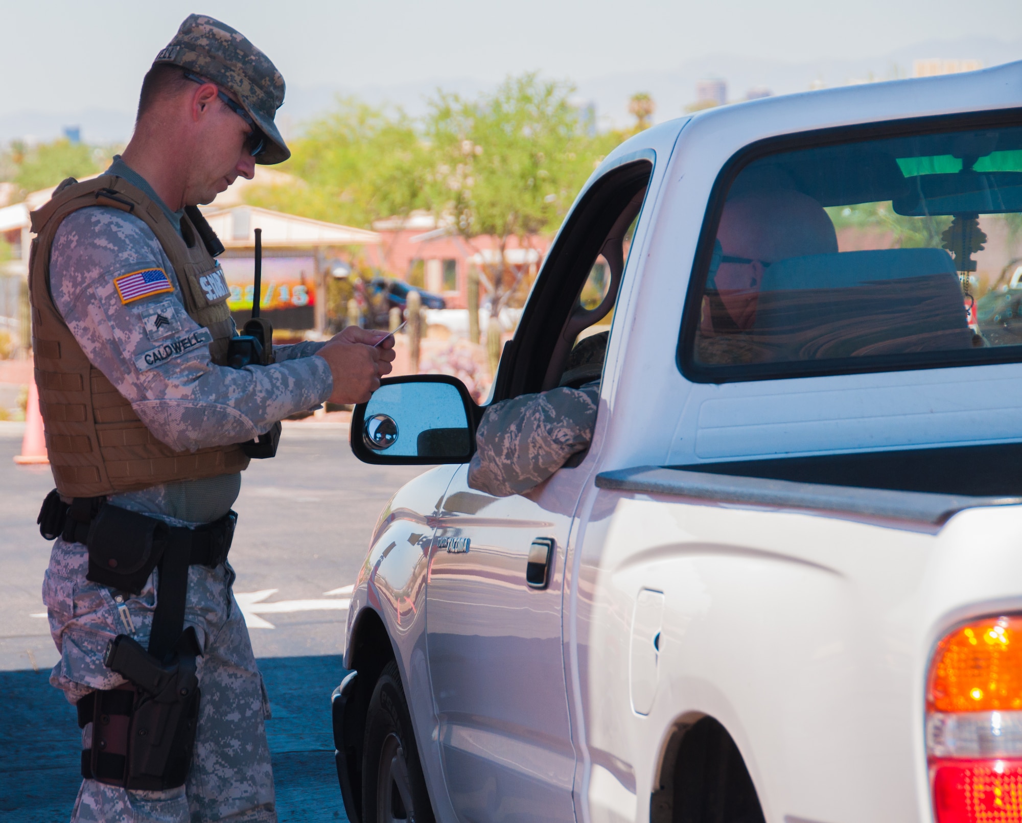 A member of the Arizona Army National Guard’s security force checks identification at the main gate of Papago Park Military Reservation, here July 22. Arizona is among several states that have recently announced it will arm service members on Guard instillations and facilities across the state under the direction of an executive order signed by Gov. Doug Ducey. (U.S. Army National Guard Photo by Spc. Wes Parrell)