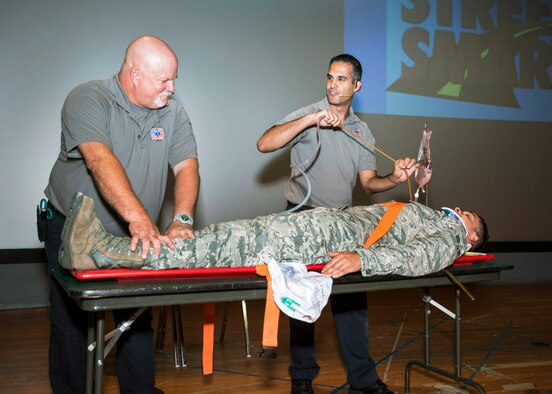 Greg McCarty and Oscar Duran, both paramedics from Miami-Dade County, Florida, give a demonstration of the tools and evasive procedures used to keep someone alive until they reach a trauma center after a traffic accident during a Street Smart briefing July 16, at Travis Air Force Base, California.  Airman 1st Class Isaiah Sylvia, a flight service center journeyman assigned to 60 Logistics Readiness Squadron, posed as the victim. (U.S. Air Force photo by T.C. Perkins Jr.)

