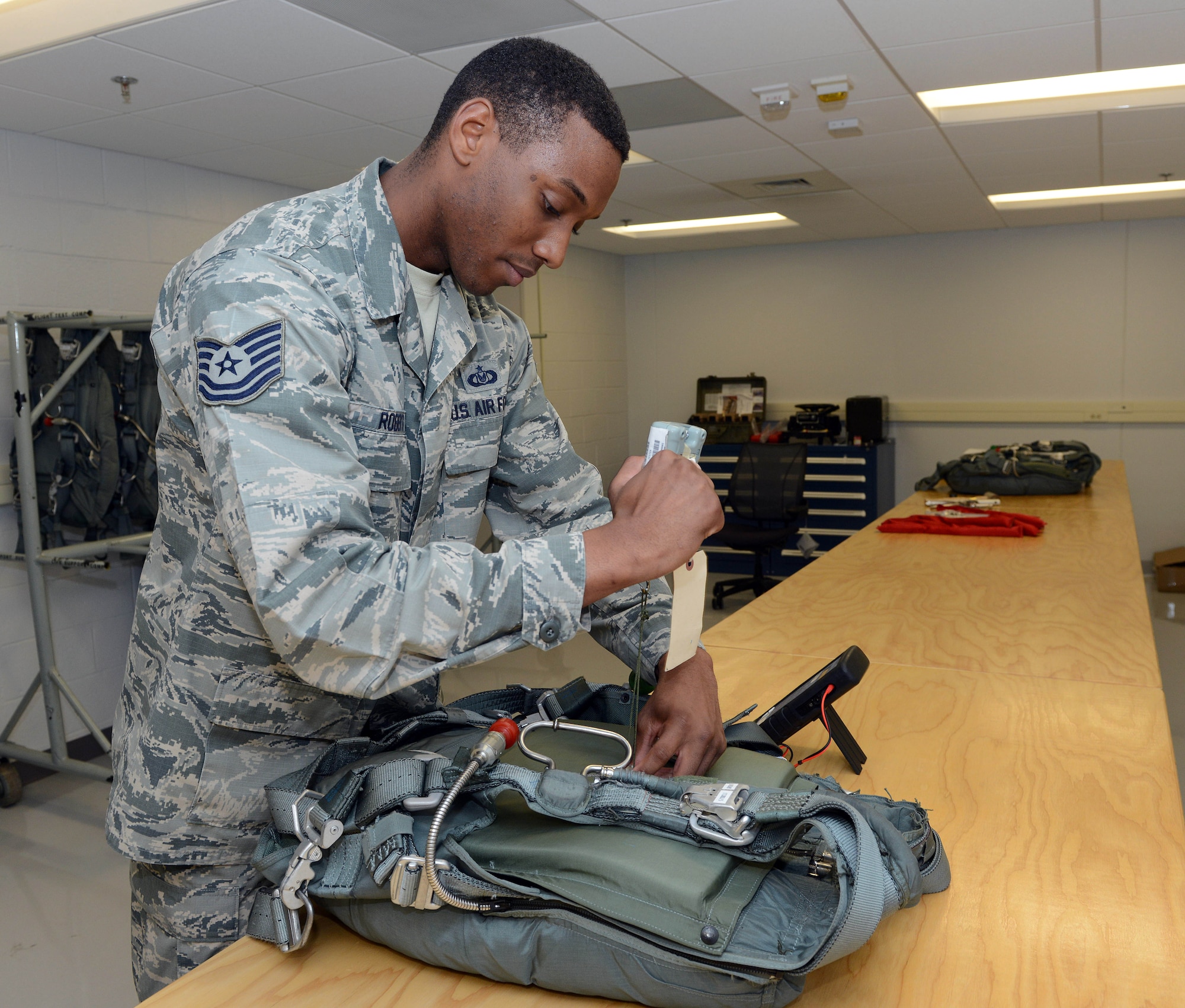 Tech. Sgt. Stephen Roberts, 339th Flight Test Squadron aircrew flight equipment technician, performs operational checks on parachute ejector snaps. (U.S. Air Force photo by Tommie Horton)