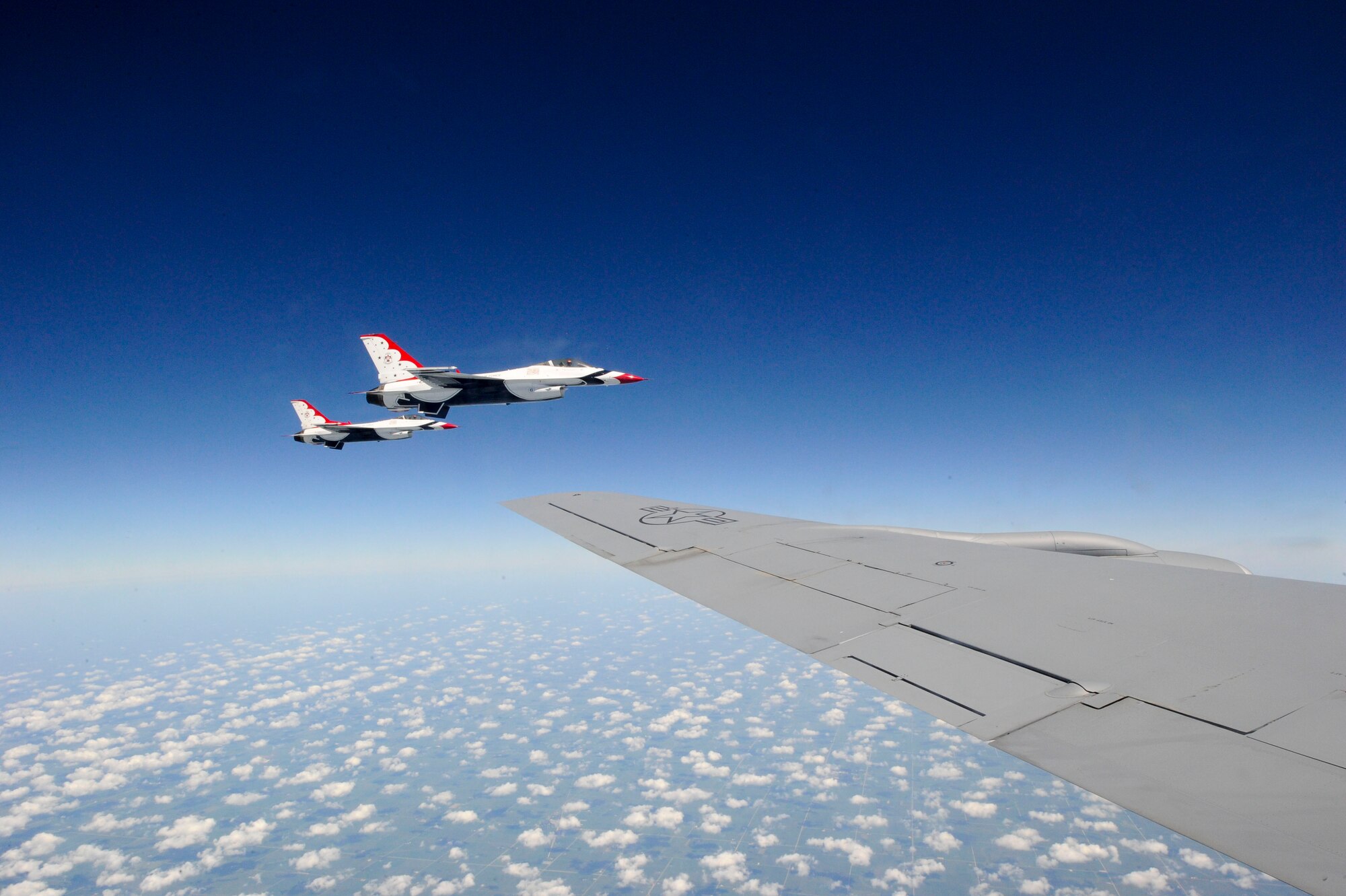 Two members of the U.S. Air Force Thunderbirds fly alongside a KC-135 Stratotanker assigned to McConnell Air Force Base, Kan., July 23, 2015. Five of the Thunderbirds were refueled during a transit from their last show in Wyoming to their next performance in Wisconsin. The F-16 Fighting Falcons they pilot burn through fuel relatively quickly, requiring the assistance of a tanker aircraft during long-distance flights. (U.S. Air Force photo by Senior Airman Victor J. Caputo)