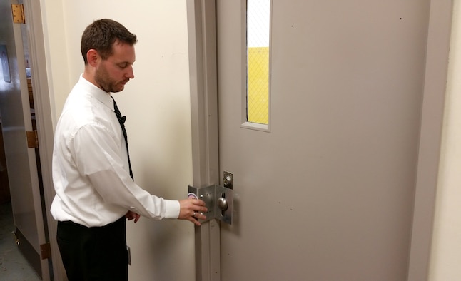 Dr. John McIntire, an engineering research psychologist with Air Force Research Laboratory's 711th Human Performance Wing, and a member of the 2015 AFRL Commanders Challenge team, demonstrates one of the four types of locks the team developed that can be deployed quickly during an active shooter situation. (Air Force photo by Bryan Ripple)