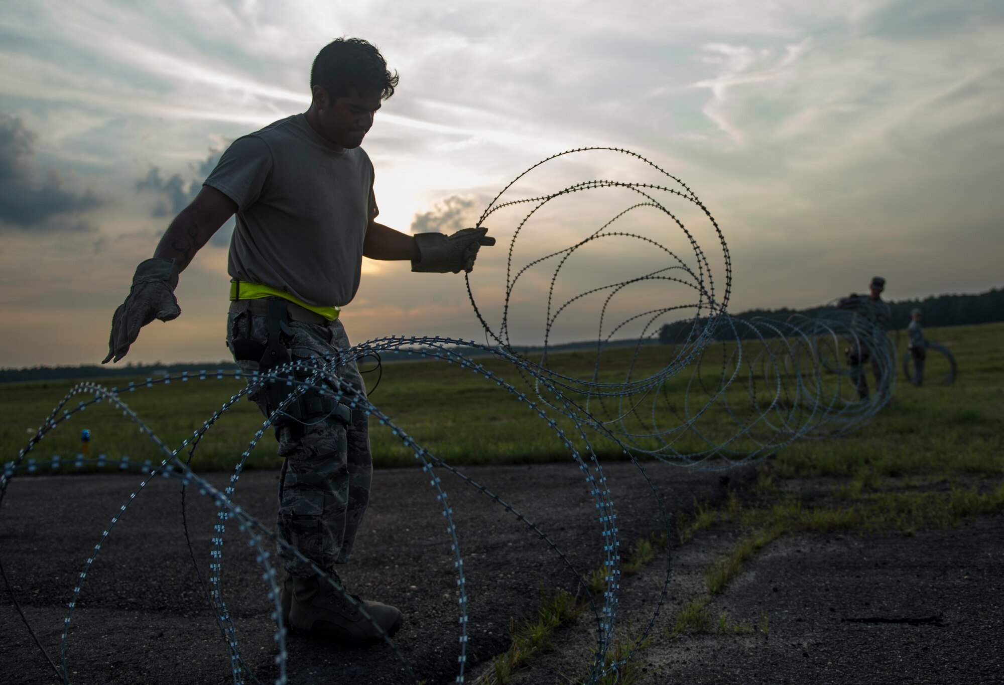 An Airman assigned to the 621st Contingency Response Wing sets up concertina wire during exercise Turbo Distribution 15-7 at Joint Base McGuire-Dix-Lakehurst, N.J., July 20, 2015. Approximately 106 Airmen stationed at Travis Air Force Base, Calif., assigned to the CRW, along with approximately 51 U.S. Army Soldiers assigned to the 690th Rapid Port Opening Element stationed at Joint Base Langley-Eustis, Va., and three members of the Defense Logistics Agency participated in the exercise, combining to make a Joint Task Force-Port Opening team. During the exercise, the U.S. Transportation Command tested the ability of the JTF-PO to distribute cargo during a humanitarian mission. (U.S. Air Force photo/Staff Sgt. Gustavo Gonzalez/RELEASED)