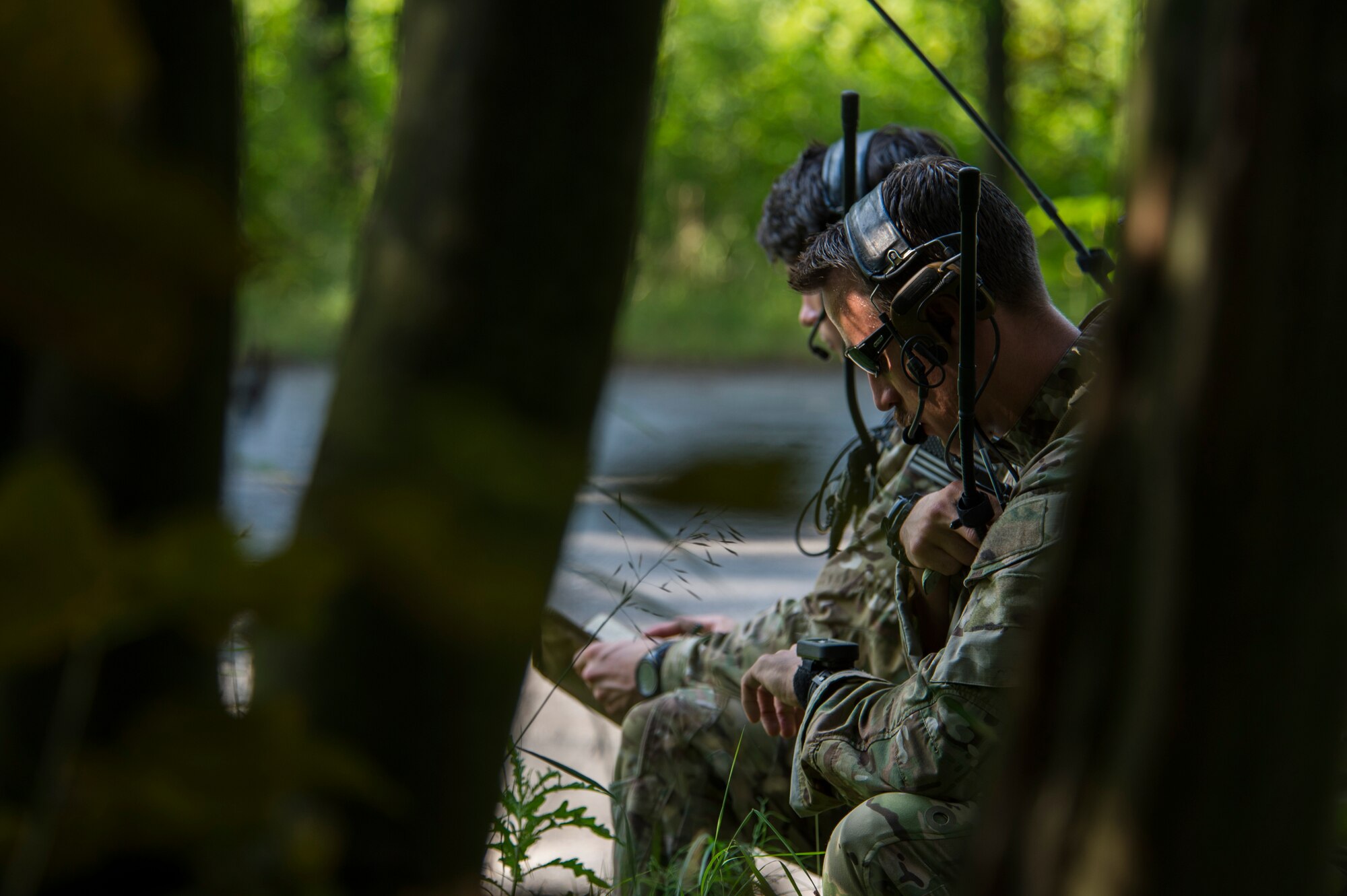 Two 321st Special Tactics Squadron combat controllers kneel in a secluded area during training at Nowe Miasto, Poland, July 22, 2015. The combat controllers communicated location coordinates and training mission objectives with A-10C Thunderbolt II aircraft pilots flying above the surrounding air space. The aircraft deployed to Poland in support of Operation Atlantic Resolve to bolster air power capabilities while underscoring the U.S. commitment to European security and stability. (U.S. Air Force photo by Airman 1st Class Luke Kitterman/Released)