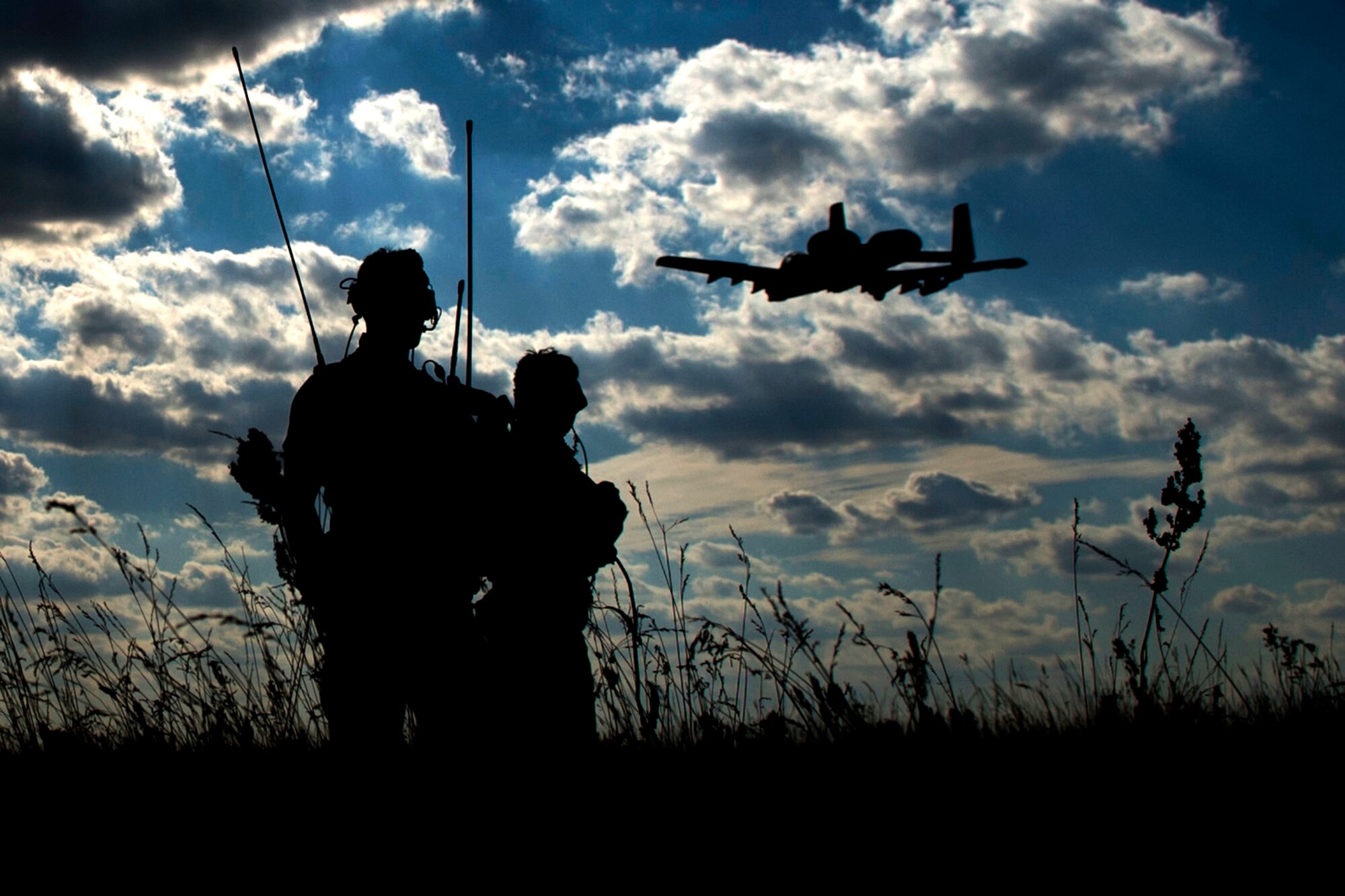 Two 321st Special Tactics Squadron combat controllers watch as a 354th Expeditionary Fighter Squadron A-10C Thunderbolt II aircraft flies over head during austere landing training at Nowe Miasto, Poland, July 20, 2015. The combat controllers set up an austere landing strip for the A-10 pilots to practice landing. The unimproved surface simulates possible landing conditions in a deployed environment. The aircraft deployed to Poland in support of Operation Atlantic Resolve to bolster air power capabilities while underscoring the U.S. commitment to European security and stability. (U.S. Air Force photo by Airman 1st Class Luke Kitterman/Released)