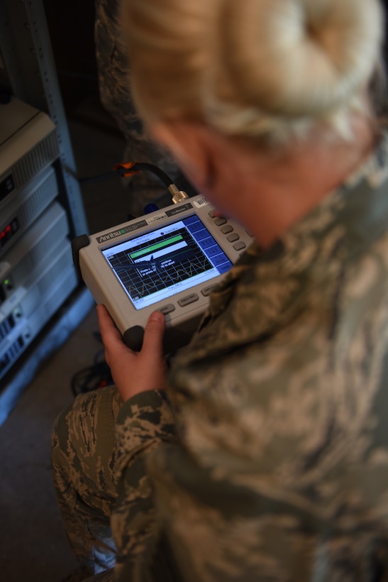 Staff Sgt. Cynthia Lose, antenna grounding project team chief, 211th Engineering Installation Squadron, reviews the cable testing results after grounding a surge protection device to the bus bar in a communications room. Testing cables is an important step in the grounding process to detect any issues within the cable lines and allows the Airmen to ensure equipment remains safe in the instance of lightening. (U.S. Air National Guard photo by Staff Sgt. Claire Behney/Released)