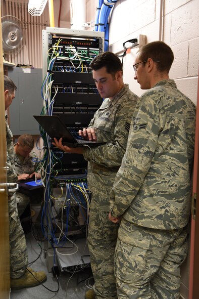 Four members of the 211th Engineering Installation Squadron video distribution team configure a secondary z-ban box in a communication room in the headquarters building of the 168th Air Refueling Wing, Eielson Air Force Base, Fairbanks, Alaska. The video distribution project was one of the four projects the 211th EIS took on during Exercise Frosty Spear, 168th ARW, where they worked to improve the video quality transmitted throughout the base. (U.S. Air National Guard photo by Staff Sgt. Claire Behney)