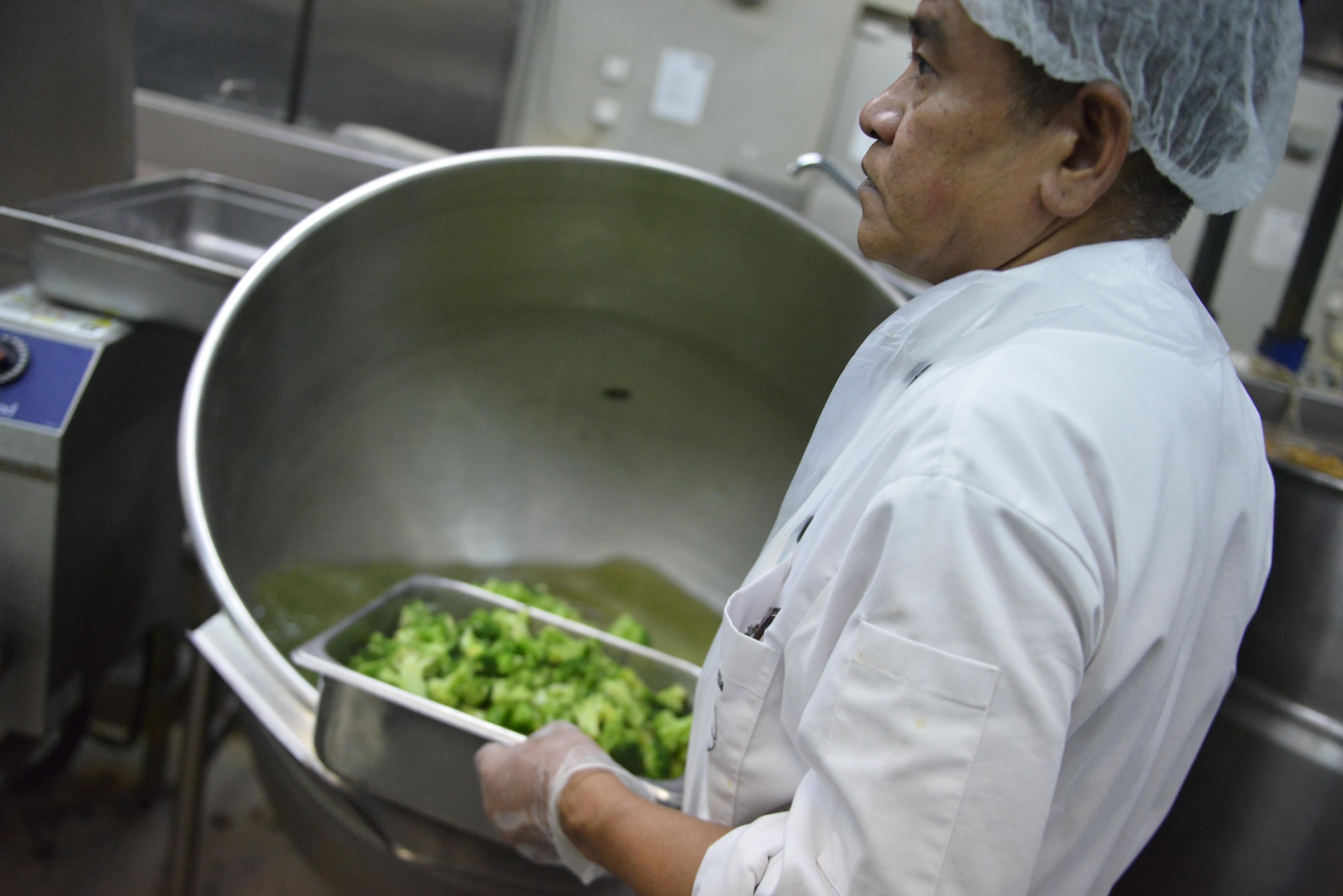 Danilo Escarilla pulls cooked broccoli out of cauldron while helping to prepare part of the day’s lunch menu at the Independence Dining Facility at Al Udeid Air Base, Qatar July 21, 2015. He has been working at Al Udeid since 2006. (U.S. Air Force photo/Staff Sgt. Alexandre Montes)