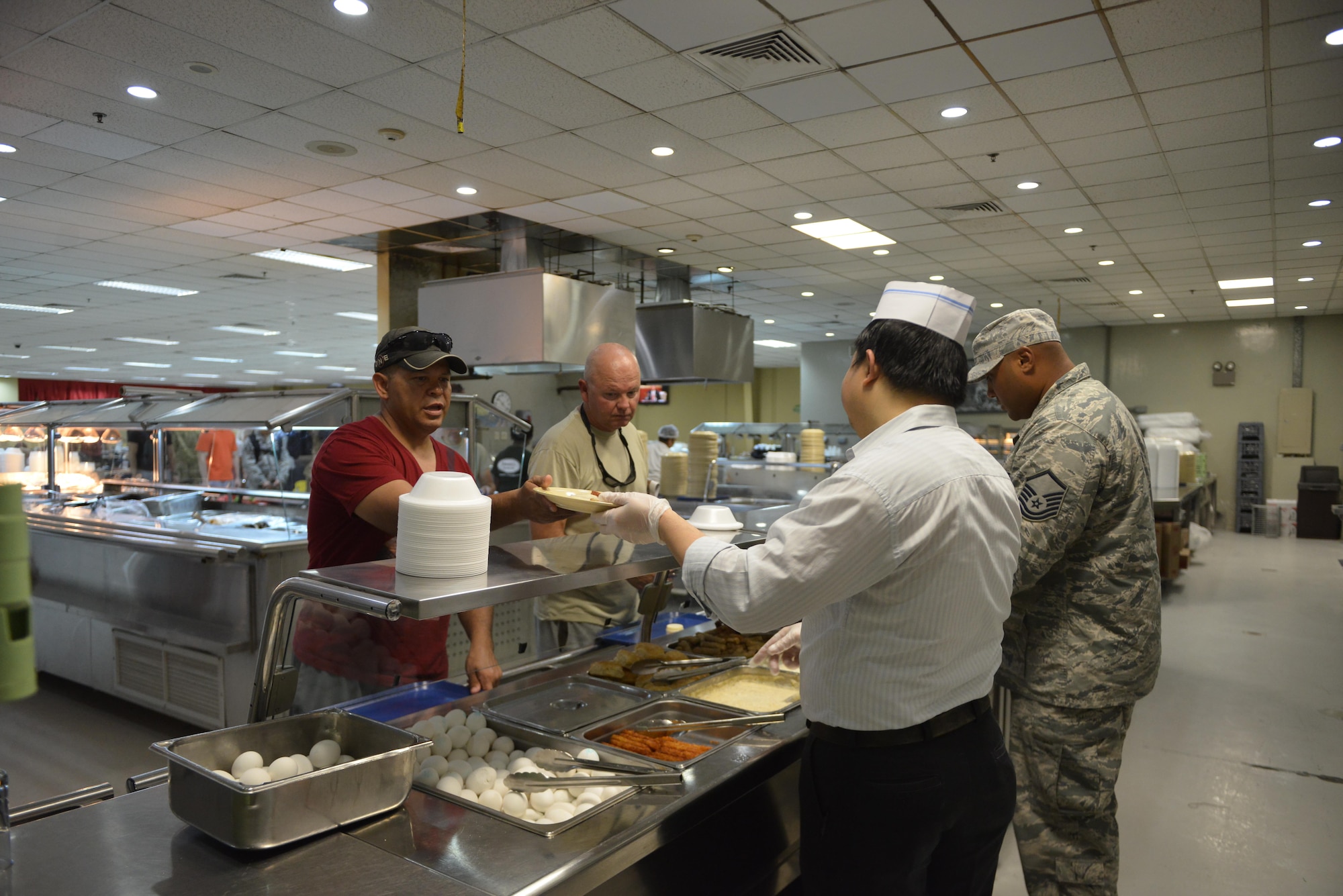Deployed members are served breakfast by dining facility cooks and MSgt Herman Brown, 379 Expeditionary Force Support Squadron  at the Independence Dining Facility at Al Udeid Air Base, Qatar July 21, 2015. (U.S. Air Force photo/Staff Sgt. Alexandre Montes)