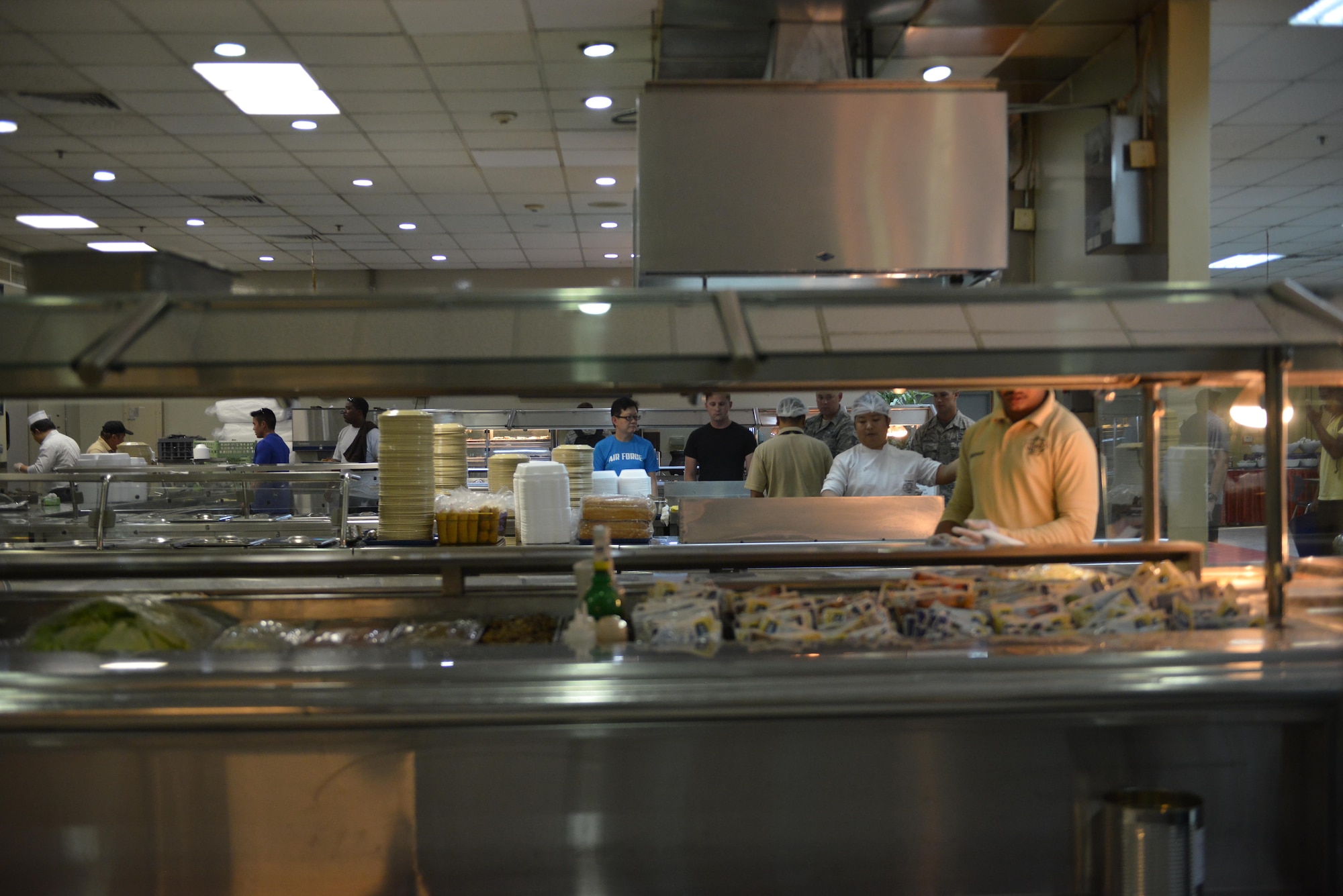 Dining facility cooks prepare one side of the dining facility for lunch while the other side is used to serve breakfast to deployed members at the Independence Dining Facility at Al Udeid Air Base, Qatar July 21, 2015. (U.S. Air Force photo/Staff Sgt. Alexandre Montes)