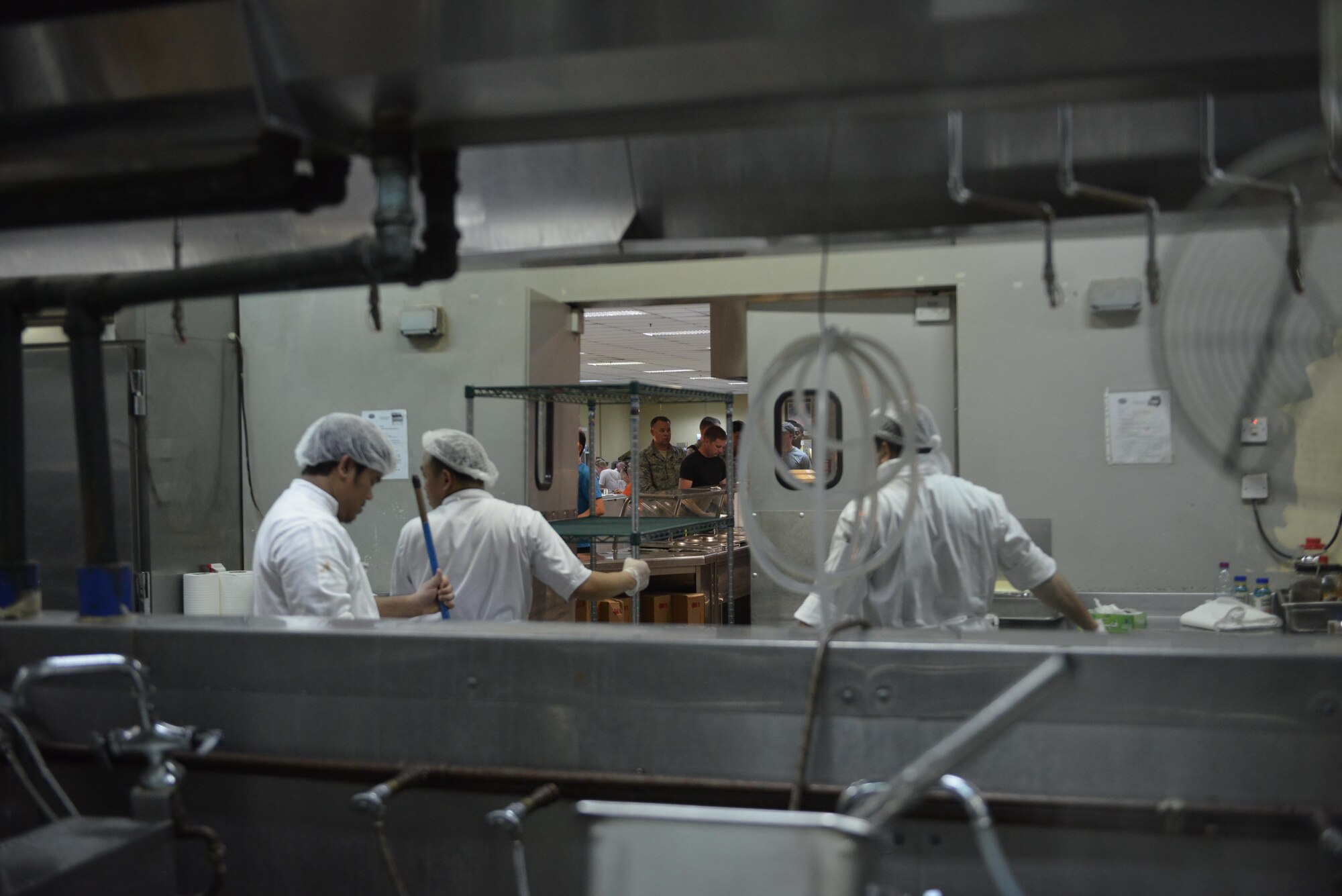 Dining facility cooks transport and prepare for the lunch menu as breakfast is still being served at the Independence Dining Facility at Al Udeid Air Base, Qatar July 21, 2015. (U.S. Air Force photo/Staff Sgt. Alexandre Montes)