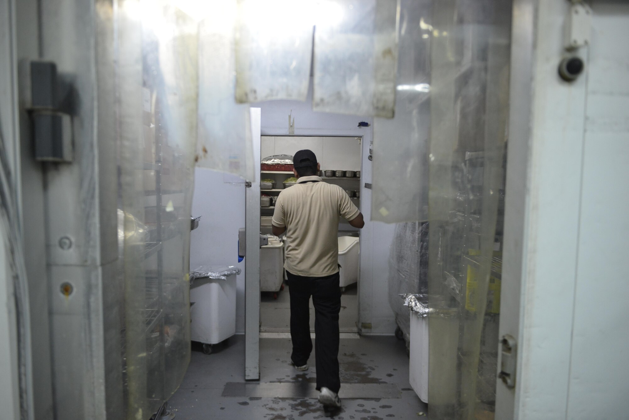A dining facility member stores a pan of food in the industrial walk-in freezer at the Independence Dining Facility at Al Udeid Air Base, Qatar July 21, 2015. (U.S. Air Force photo/Staff Sgt. Alexandre Montes)