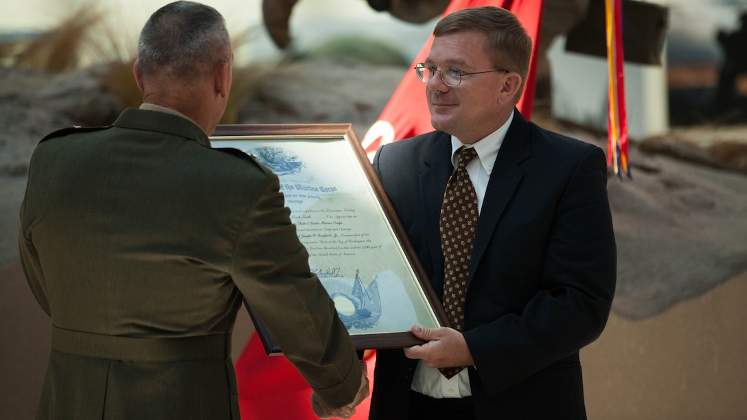 Mark Noah, the executive director of History Flight, receives the title of Honorary Marine during a ceremony held at the National Marine Corps Museum, at Triangle, Virginia, July 24. History Flight uses radar, cadaver dogs and cross referencing old military maps with high resolution aerial maps of the island today to finds Marine, who were thought to be lost after the island hopping campaign of World War II.