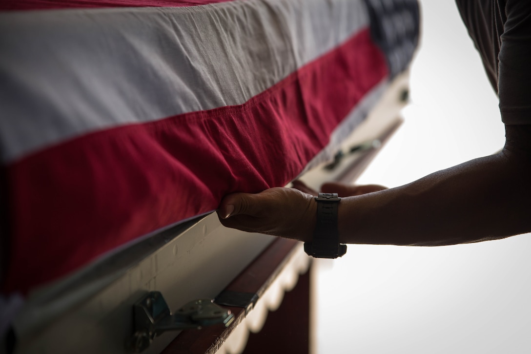 A Defense POW/MIA Accounting Agency worker preps a casket of remains for a repatriation ceremony, July 25, 2015, in Tarawa, Kiribati. The ceremony honored approximately 36 Marines who fought and died during the Battle of Tarawa in World War II. The remains were loaded onto a C-130J Hercules aircraft and prepped for their return home to the United States. 