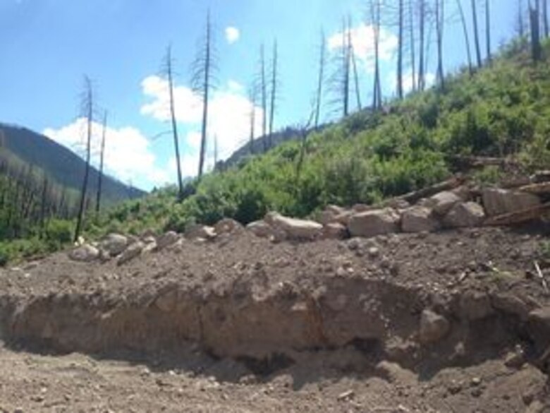 As Climate Changes, Santa Clara Strives To Become Resilient To Worsening Fires, Floods: High up in the Santa Clara Canyon’s burn-scarred flood hazard zone, a battered tree stump protrudes from new debris and sediment deposited by raging floodwaters. ‘After one event, an area may be incised by 20 feet,’ said pueblo forester Matthew Tafoya. ‘Then another event comes in, and it drops material in that area. You may go from minus 20 feet to plus 20, up and down, up and down.’ Margaret Wright/The New Mexican