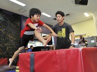 Riki Kaneko from Chatan Elementary School jumps a ninja obstacle block at the Youth Center during a visit on Kadena Air Base, Japan, July 23, 2015. A total of 14 children from Chatan Town elementary schools participated in the culture exchange program. During their visit, the children ate lunch with and played with American children around their own ages in an effort to learn more about American culture and language. (U.S. Air Force photo by Naoto Anazawa/Released)