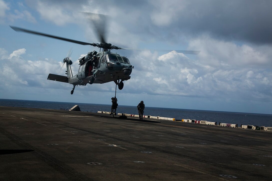 INDIAN OCEAN (July 24, 2015) U.S. Marines with the 15th Marine Expeditionary Unit’s Maritime Raid Force fast-rope out of an MH-60S Sea Hawk, from the “Blackjacks” of Helicopter Sea Combat Squadron 21, onto the amphibious assault ship USS Essex (LHD 2). These Marines are assigned to India Company, Battalion Landing Team 3rd Battalion, 1st Marine Regiment, 15th MEU, and are members of the MRF’s security element. The Marines practiced fast-roping onto the flight deck and simulated clearing the ship. Elements of the 15th MEU, based out of Camp Pendleton, California, and embarked aboard the Essex, are conducting naval operations in the 6th Fleet areas of operation in support of U.S. national security interests in Europe and Africa. (U.S. Marine Corps photo by Cpl. Anna Albrecht/Released)