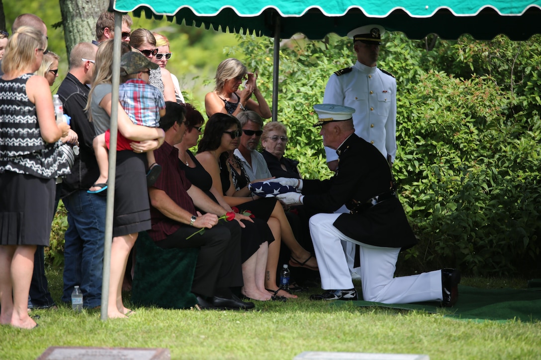 Lt. Gen. Richard P. Mills, commander of Marine Forces Reserve, presents a folded flag to the widow of Sgt. Carson Holmquist, a motor transport maintenance chief with Battery M, 3rd Battalion, 14th Marine Regiment, 4th Marine Division, Marine Forces Reserve, during his funeral July 25, 2015 in Grantsburg, Wis. Holmquist, along with three other Marines and a Sailor, was killed in an attack at the Naval Operation Support Center and Marine Corps Reserve Center in Chattanooga, Tenn. on July 16, 2015. Marines, family, friends and the community of Grantsburg gathered to honor the memory and sacrifice of Holmquist and his fallen brothers-in-arms.