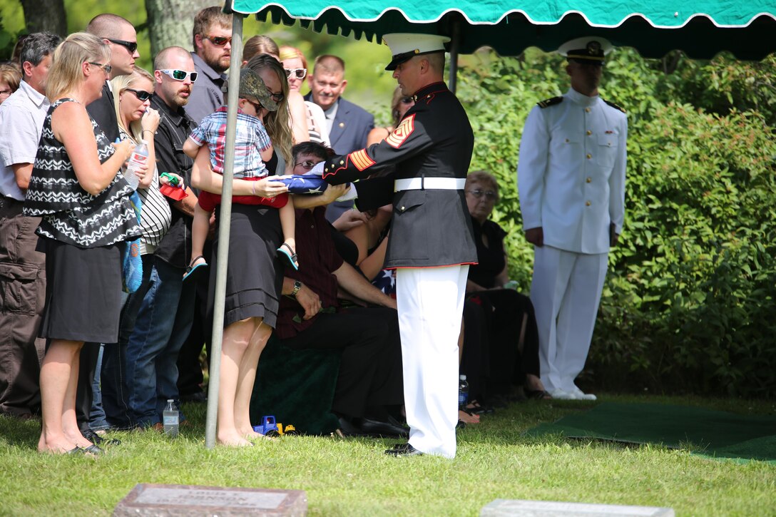 First Sgt. Timothy Dennison, the detachment first sergeant for Marine Wing Support Squadron 471, 4th Marine Aircraft Wing, presents a folded flag to the son of Sgt. Carson Holmquist, a motor transport maintenance chief with Battery M, 3rd Battalion, 14th Marine Regiment, 4th Marine Division, Marine Forces Reserve, during his funeral July 25, 2015 in Grantsburg, Wis. Holmquist, along with three other Marines and a Sailor, was killed in an attack at the Naval Operation Support Center and Marine Corps Reserve Center in Chattanooga, Tenn. on July 16, 2015. Marines, family, friends and the community of Grantsburg gathered to honor the memory and sacrifice of Holmquist and his fallen brothers-in-arms. 