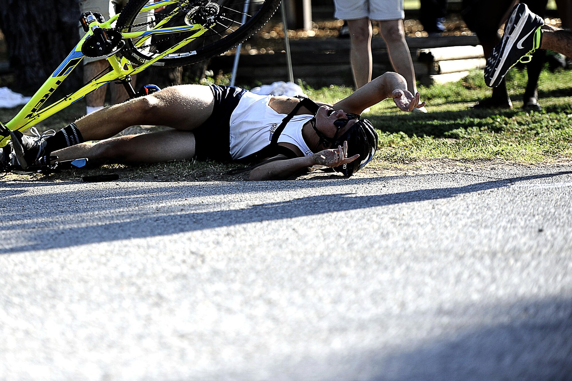 U.S. Air Force Airman 1st Class Isaac Forest, 17th Communications Squadron, wrecks his bicycle as he completes the tag-out to his teammate for the running portion of the 8th Annual Goodfellow Triathlon at the Goodfellow Air Force Base Recreation Camp in San Angelo, Texas, July 25, 2015. The competition allowed individuals to compete on their own or as a team. For some, the transition between each event was difficult. (U.S. Air Force photo by Tech. Sgt. Austin Knox/Released) 