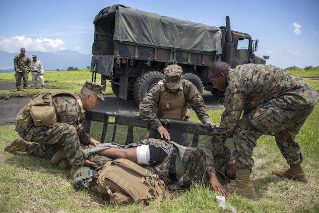 Hospital Corpsman 3rd Class Daniel Valerio, left, Hospital Corpsman Mc Joe Evans Bautista, center, and Hospital Corpsman 3rd Class Trevor A. Tisby, right, stationed with Combat Logistics Company 36 aboard Marine Corps Air Station Iwakuni, Japan, place Sgt. Kendrick Moore, a motor transport operator with CLC-36, onto the stretcher during Exercise Dragon Fire 2015 at Combined Arms Training Center Camp Fuji, Japan, July 20, 2015. Moore simulated an unexpected injury during this training scenario that allowed the corpsmen to respond as if there was a real emergency. Dragon Fire reinforces Marines’ and Sailors’ combat mindset to prepare them for the mental and physical stresses of a combat zone.