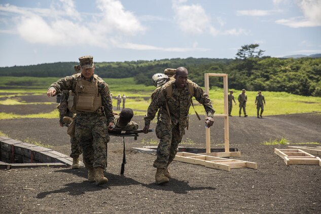 Hospital Corpsman Mc Joe Evans Bautista, left, and Hospital Corpsman 3rd Class Trevor A. Tisby, right, stationed with Combat Logistics Company 36 aboard Marine Corps Air Station Iwakuni, Japan, carry Sgt. Kendrick Moore, a motor transport operator with CLC-36, to a safety vehicle during Exercise Dragon Fire 2015 at Combined Arms Training Center Camp Fuji, Japan, July 20, 2015. Dragon Fire enables Marines and Sailors to engage their combat mindset to prepare for the mental and physical stresses of a combat zone. Moore simulated an unexpected injury during this training scenario that allowed the corpsmen to respond as if there was a real emergency.