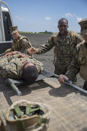 Hospital Corpsman 3rd Class Daniel Valerio, left, Hospital Corpsman 3rd Class Trevor A. Tisby, center, and Hospital Corpsman Mc Joe Evans Bautista, right, stationed with Combat Logistics Company 36 aboard Marine Corps Air Station Iwakuni, Japan, place Sgt. Kendrick Moore, a motor transport operator with CLC-36, onto a safety vehicle during Exercise Dragon Fire 2015 at Combined Arms Training Center Camp Fuji, Japan, July 20, 2015. Dragon Fire allows Marines and Sailors to engage their combat mindset to prepare for the mental and physical stresses of a combat zone. Moore simulated an unexpected injury during this training scenario that allowed the corpsmen to respond as if there was a real emergency.