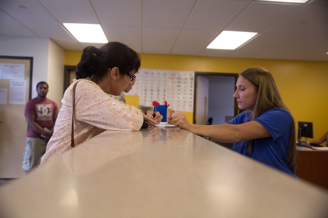Kelsey Zukowski, a clerk with the vehicle registration office, helps a spouse July 20, 2015, at the vehicle registration office at building 1095. The office hours of the vehicle registration office are Monday through Friday from 7:30 a.m. until 4:30 p.m. The mission of Marine Corps Base Hawaii is to provide facilities, programs and services in direct support of units, individuals and families to enhance and sustain combat readiness for all operating forces and tenant organizations aboard the installation. (U.S. Marine Corps Cpl. Khalil Ross/Released)