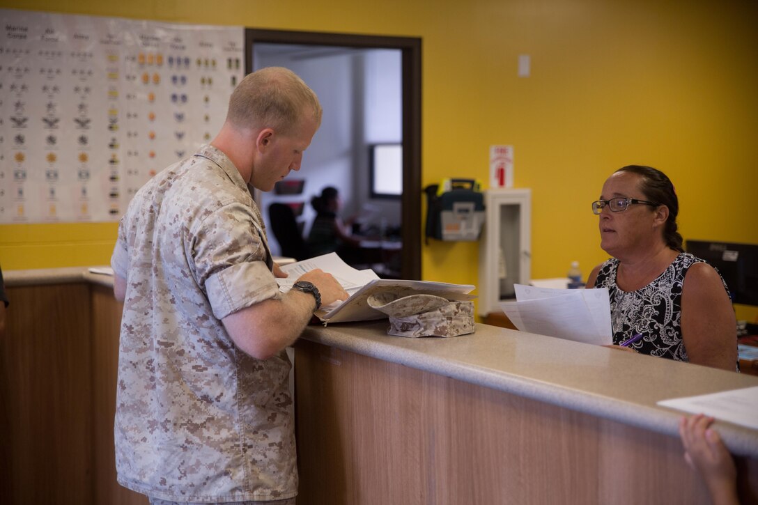 Karen Punahele, a clerk with the Provost Marshal's Office, helps a Marine with his vehicle registration July 20, 2015, at the vehicle registration office at building 1095. The office hours of the vehicle registration office are Monday through Friday from 7:30 a.m. until 4:30 p.m. (U.S. Marine Corps photo by Cpl. Khalil Ross/Released)