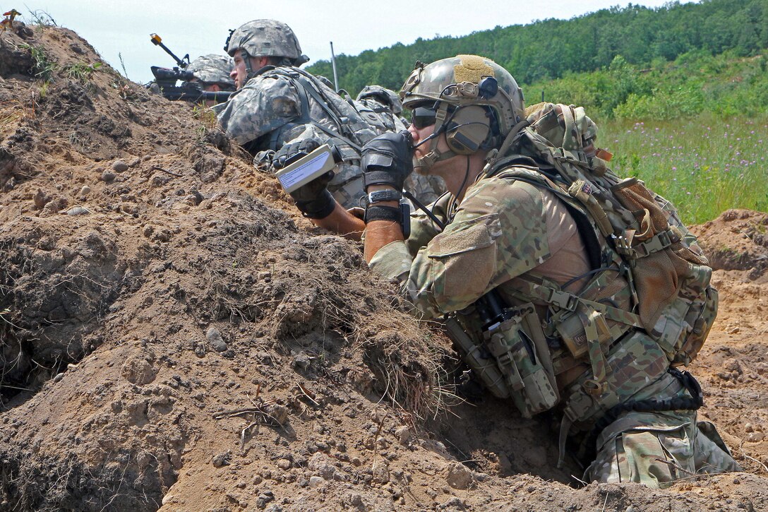 A U.S. airman, foreground, monitors the field then calls in close air support during a combined live-fire exercise as part of Northern Strike 15 on Camp Grayling Joint Maneuver Training Center, Mich., July 20, 2015. The airman is a joint terminal attack controller assigned to the New York National Guard's 274th Air Support Operations Squadron. Northern Strike assesses joint air-to-ground capability and involves hundreds of military personnel from 20 different states as well as Canada, Latvia, Poland and Australia.