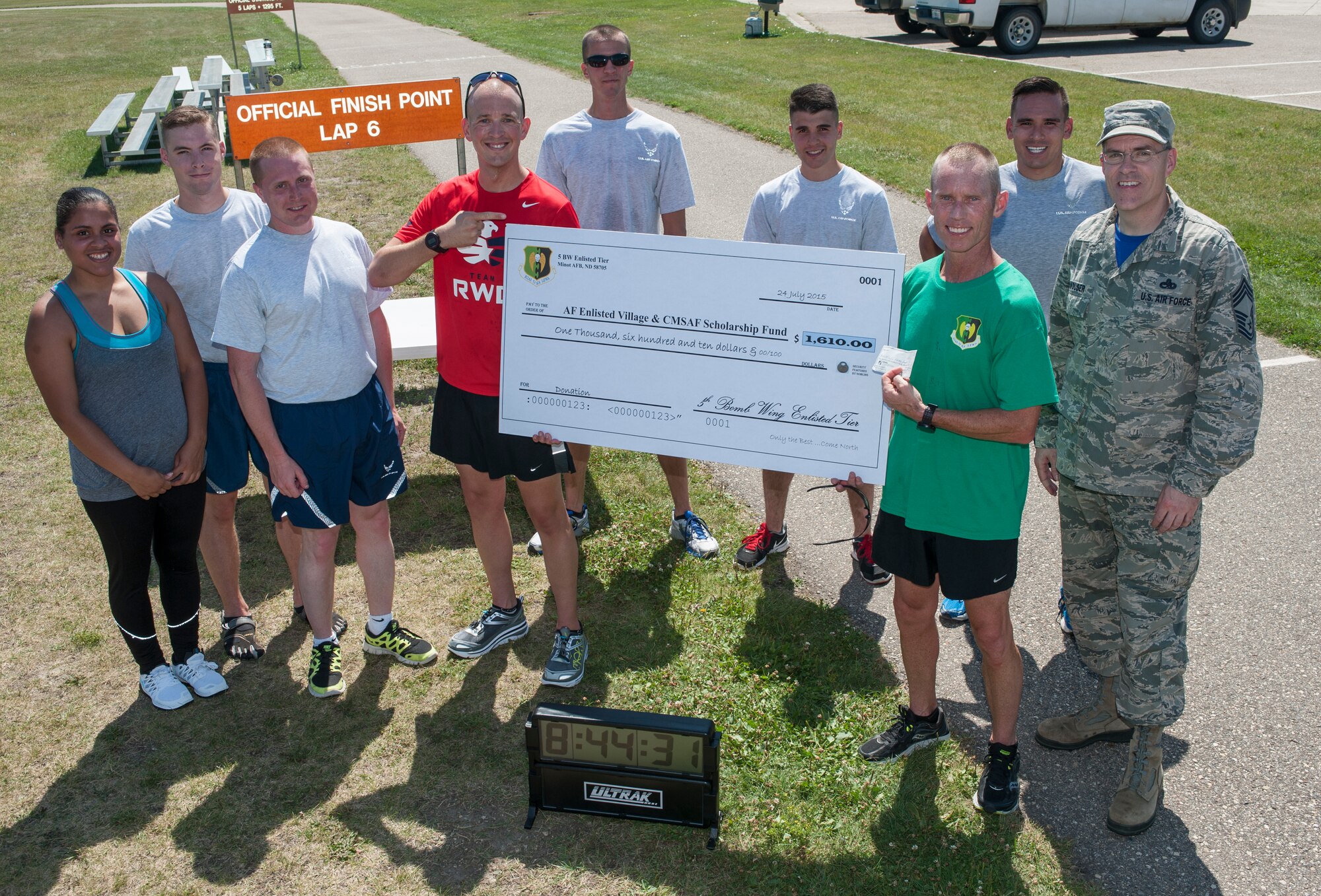 Chief Master Sgt. Geoff Weimer, 5th Bomb Wing command chief, is presented a check at the outdoor track finish line after running 52 miles at Minot Air Force Base, N.D., July 24, 2015. Weimer completed the run to support the Air Force Enlisted Village and Chief Master Sergeant Scholarship Fund and was able to raise $1,733.60. (U.S. Air Force photo/Senior Airman Stephanie Morris)
