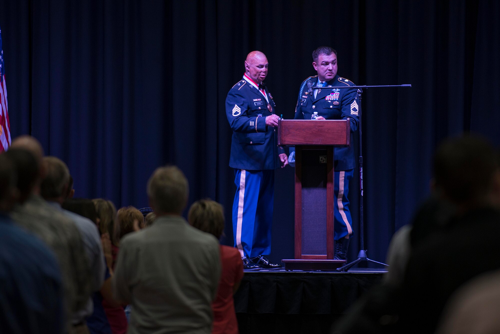 U.S. Air Force Airmen, in attendance with the Wichita Falls community, listen to Medal of Honor recipient retired U.S. Army Master Sgt. Leroy Petry and retired U.S. Army Staff Sgt. Shilo Harris as they share the stage during the Wichita Falls Leadership Breakfast at the Kay Yeager Coliseum in Wichita Falls, Texas, July 24, 2015. Petry and Harris used their experience and disabilities to inspire other wounded warriors to overcome their challenges. Petry lost his hand while tossing a live grenade to save his soldiers. Harris suffered severe burns and injuries from an explosion that mangled his Humvee, killing three of his partners. (U.S. Air Force photo by Senior Airman Kyle Gese/Released)
