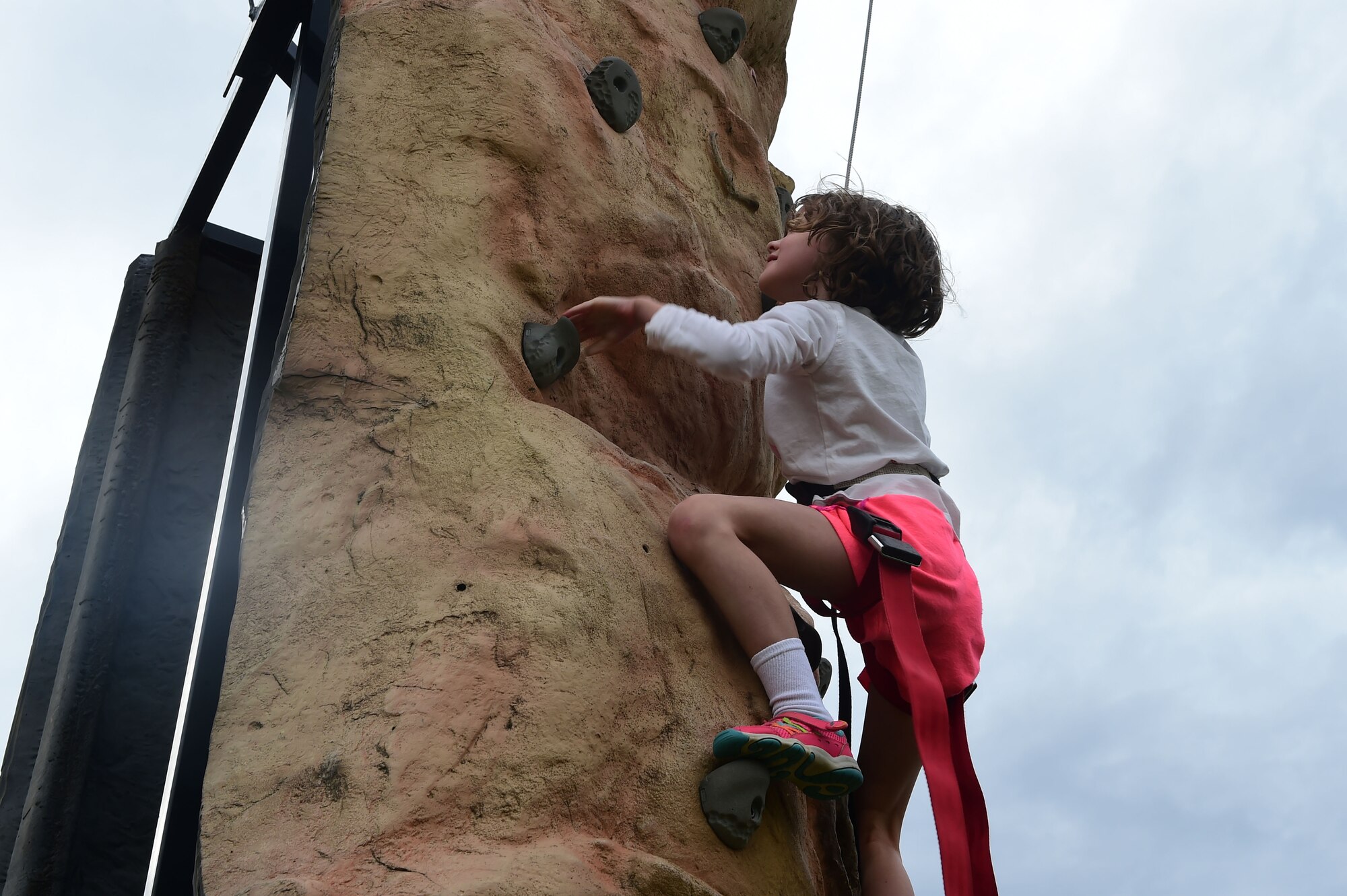 A girl climbs a rock wall during FunFest July 24, 2015, at Buckley Air Force Base, Colo. FunFest is an annual base-wide event that includes family-friendly games and activities, community involvement and local business sponsors. (U.S. Air Force photo by Airman 1st Class Luke W. Nowakowski/Released)