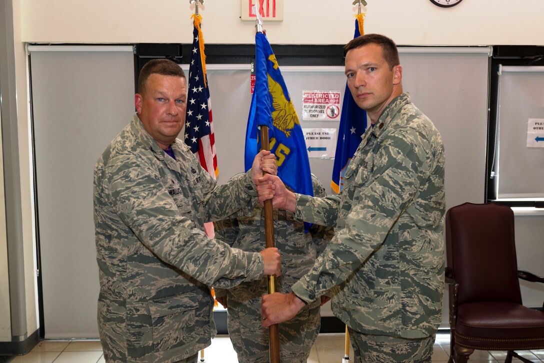 Col. Matthew Wallace, 45th Mission Support Group commander, left, presents Maj. Jonathan Carter, 45th LRS commander, with the 45th LRS guidon during a change of command ceremony, July 17, 2015, at Patrick Air Force Base, Fla. Changes of command are a military tradition representing the transfer of responsibilities from the presiding officials to the upcoming official. (U.S. Air Force photo/Cory Long) (Released) 