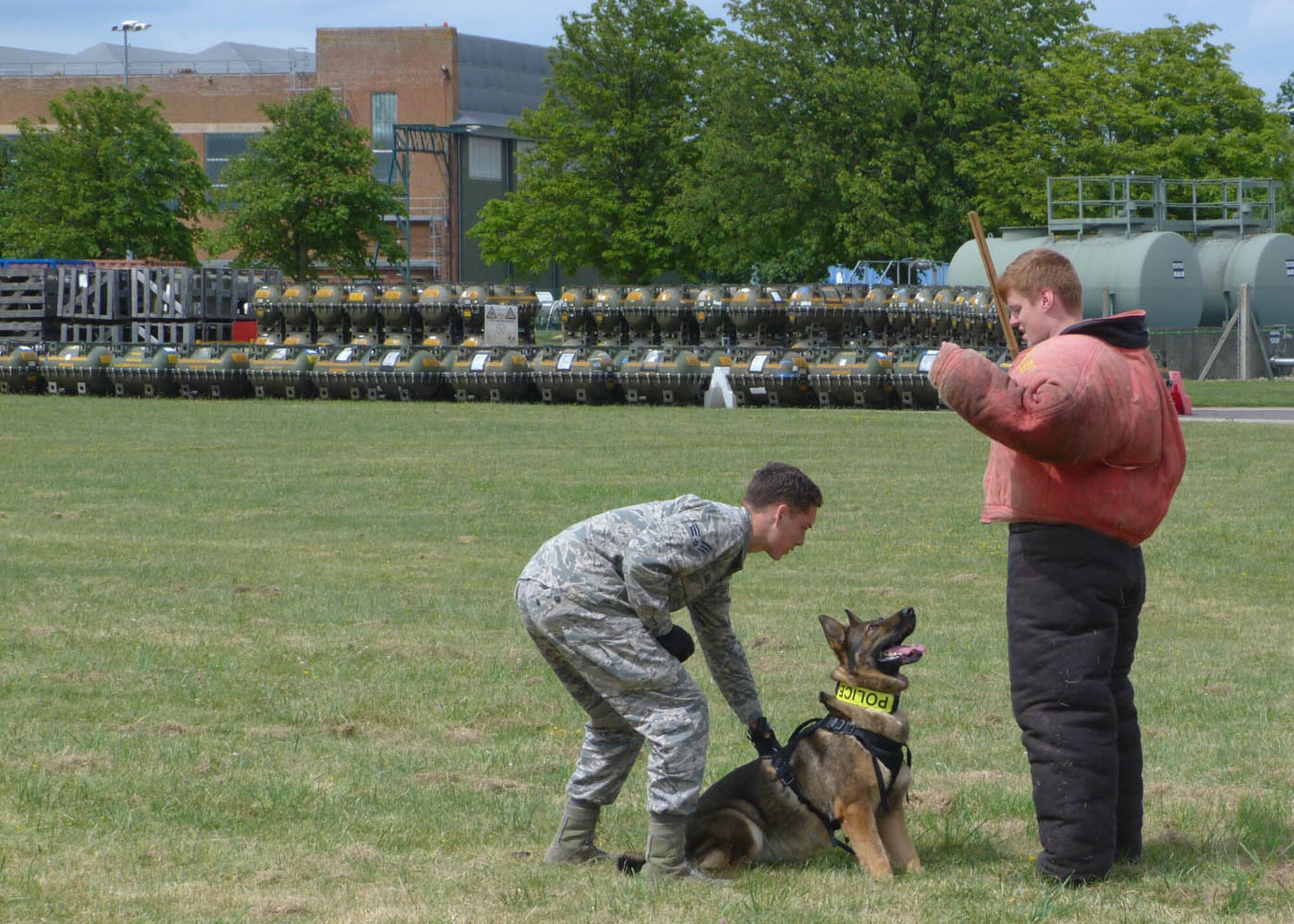 U.S. Air Force Senior Airman Jason Soliz, left, 100th Security Forces Squadron Military Working Dog handler from Milpitas, Calif., restrains MWD Gina as she guards “bad guy” Corporal Nathan Watson, RAF Marham police dog handler from Newark, Nottinghamshire, England, at the “Family and Friends” open day July 23, 2015, on RAF Marham, England. Team Mildenhall also provided assets including a CV-22 Osprey and an MC-130J Commando II at the event, attended by several thousand guests. The day also included air displays from a variety of aircraft. (U.S. Air Force photo by Karen Abeyasekere/Released)