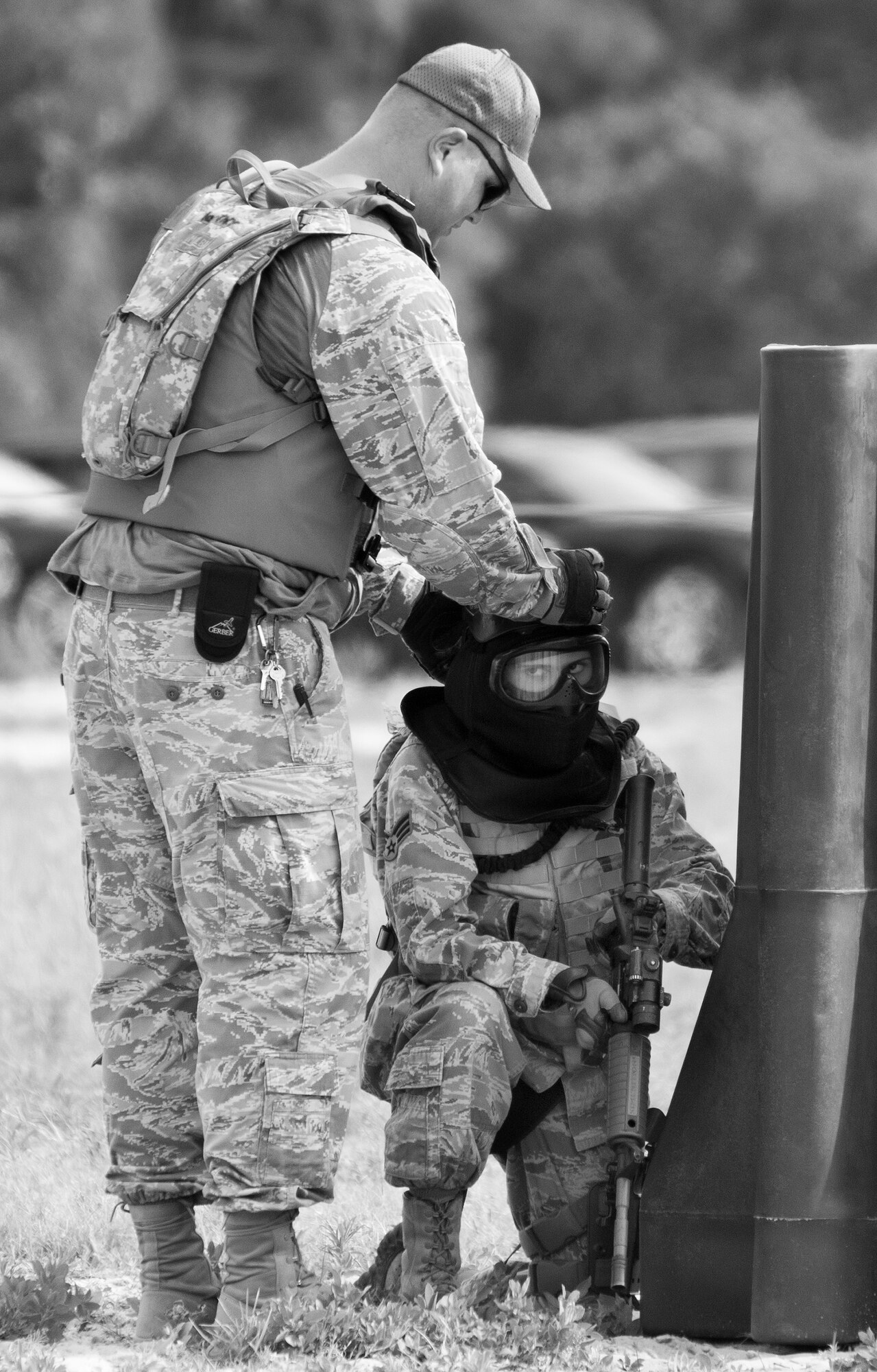 A 96th Security Forces Squadron instructor helps an Airman secure her helmet during a shoot, move and communicate drill in June at Eglin Air Force Base, Fla.  The mandatory training requirement is in addition to annual weapons qualification training.  The exercise consists of Airmen firing simmunition ammo while advancing toward, away from and to the side of a target.  This is followed by a building sweep and clear drill.  The Defenders perform the highly kinetic training at Eglin’s Base Tango range.  The range was previously used for security forces pre-deployment training.  (U.S. Air Force photo/Samuel King Jr.)