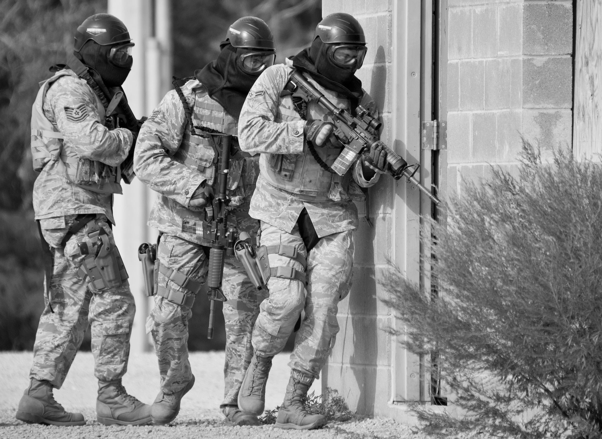 A team of 96th Security Forces Squadron Airmen advance into a building entrance during a shoot, move and communicate drill in June at Eglin Air Force Base, Fla.  The mandatory training requirement is in addition to annual weapons qualification training.  The exercise consists of Airmen firing simmunition ammo while advancing toward, away from and to the side of a target.  This is followed by a building sweep and clear drill.  The Defenders perform the highly kinetic training at Eglin’s Base Tango range.  The range was previously used for security forces pre-deployment training.  (U.S. Air Force photo/Samuel King Jr.)