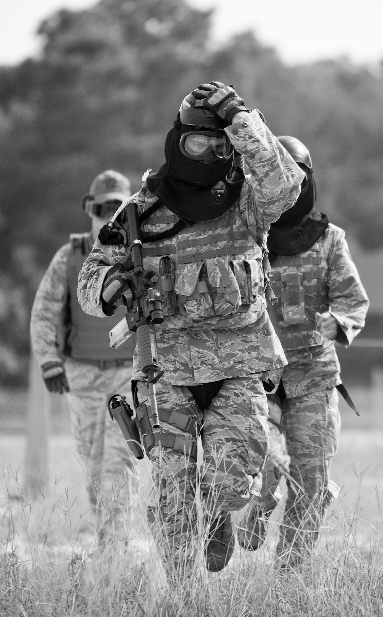 A 96th Security Forces Squadron Airman holds onto his helmet as he advances to a barrier during a shoot, move and communicate drill at Eglin Air Force Base, Fla.  The mandatory training requirement is in addition to annual weapons qualification training.  The exercise consists of Airmen firing simmunition ammo while advancing toward, away from and to the side of a target.  This is followed by a building sweep and clear drill.  The Defenders perform the highly kinetic training at Eglin’s Base Tango range.  The range was previously used for security forces pre-deployment training.  (U.S. Air Force photo/Samuel King Jr.) 