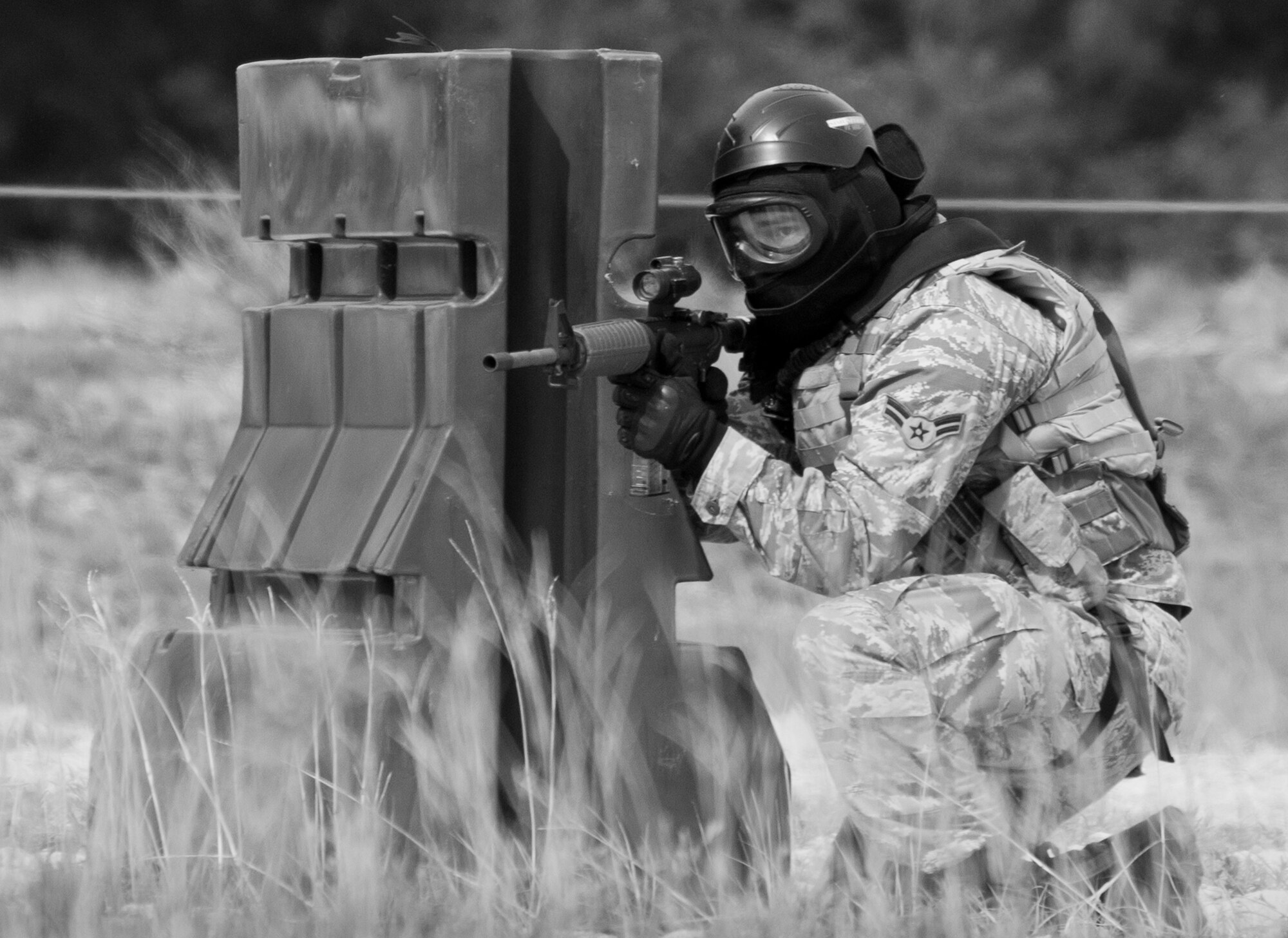 A 96th Security Forces Squadron Airman waits to advance during a shoot, move and communicate drill at Eglin Air Force Base, Fla.  The mandatory training requirement is in addition to annual weapons qualification training.  The exercise consists of Airmen firing simmunition ammo while advancing toward, away from and to the side of a target.  This is followed by a building sweep and clear drill.  The Defenders perform the highly kinetic training at Eglin’s Base Tango range.  The range was previously used for security forces pre-deployment training.  (U.S. Air Force photo/Samuel King Jr.)