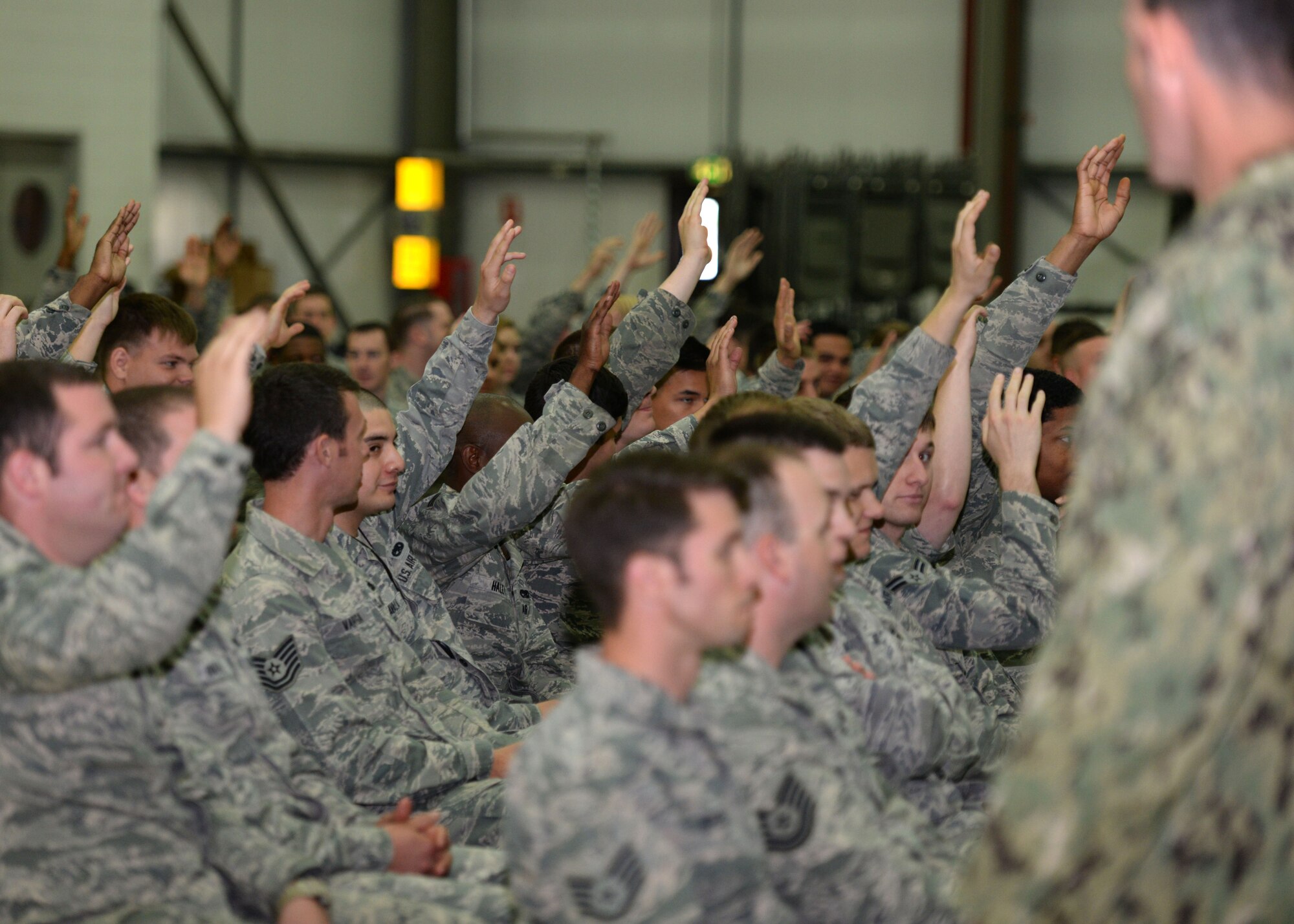 Air Commandos of the 352nd Special Operations Wing, raise their hands so U.S. Navy Command Master Chief Petty Officer Andrew Harrison, SOCEUR senior enlisted leader, can select volunteers for a discussion during an all hands call July 23, 2015, on RAF Mildenhall, England. Harrison asked the service members questions on geography, popular culture and their chain of command to get to know the team. (U.S. Air Force photo by Gina Randall/Released)