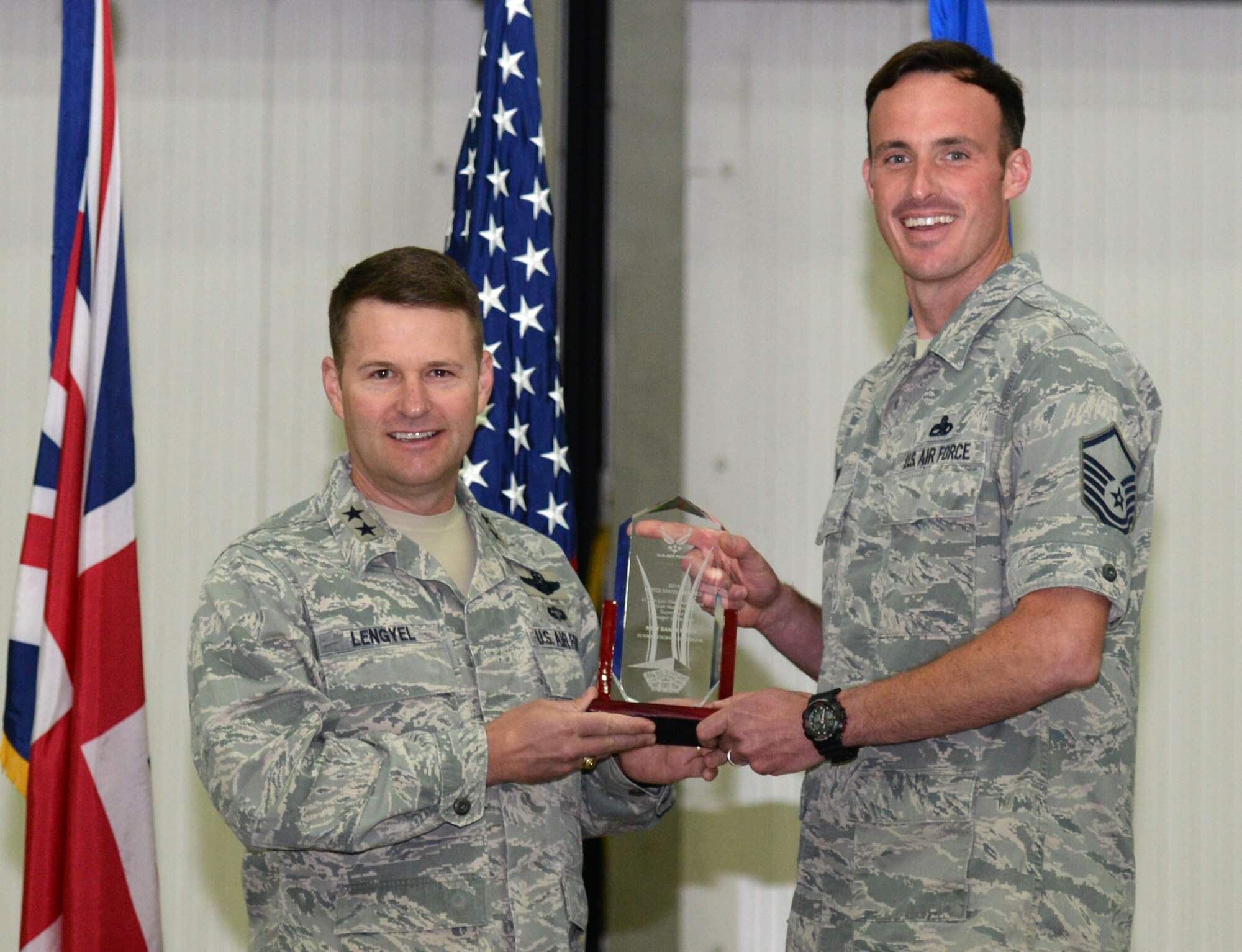 U.S. Air Force Maj. Gen. Gregory J. Lengyel, left, U.S. Special Operations Command - Europe commander, presents U.S. Air Force Master Sgt. Daniel Wey, 352nd Special Operations Maintenance Squadron CV-22B Production Superintendent from St. Paul, Minn., with the Air Force Lt. Gen. Leo Marquez Award for maintenance supervision, during an all-hands call July 23, 2015, on RAF Mildenhall, England. Wey won the Air Force level award for his leadership skills and display of heroism when responding to the aid of a local child who had fallen from a tree and suffered a head injury. (U.S. Air Force photo by Gina Randall/Released)