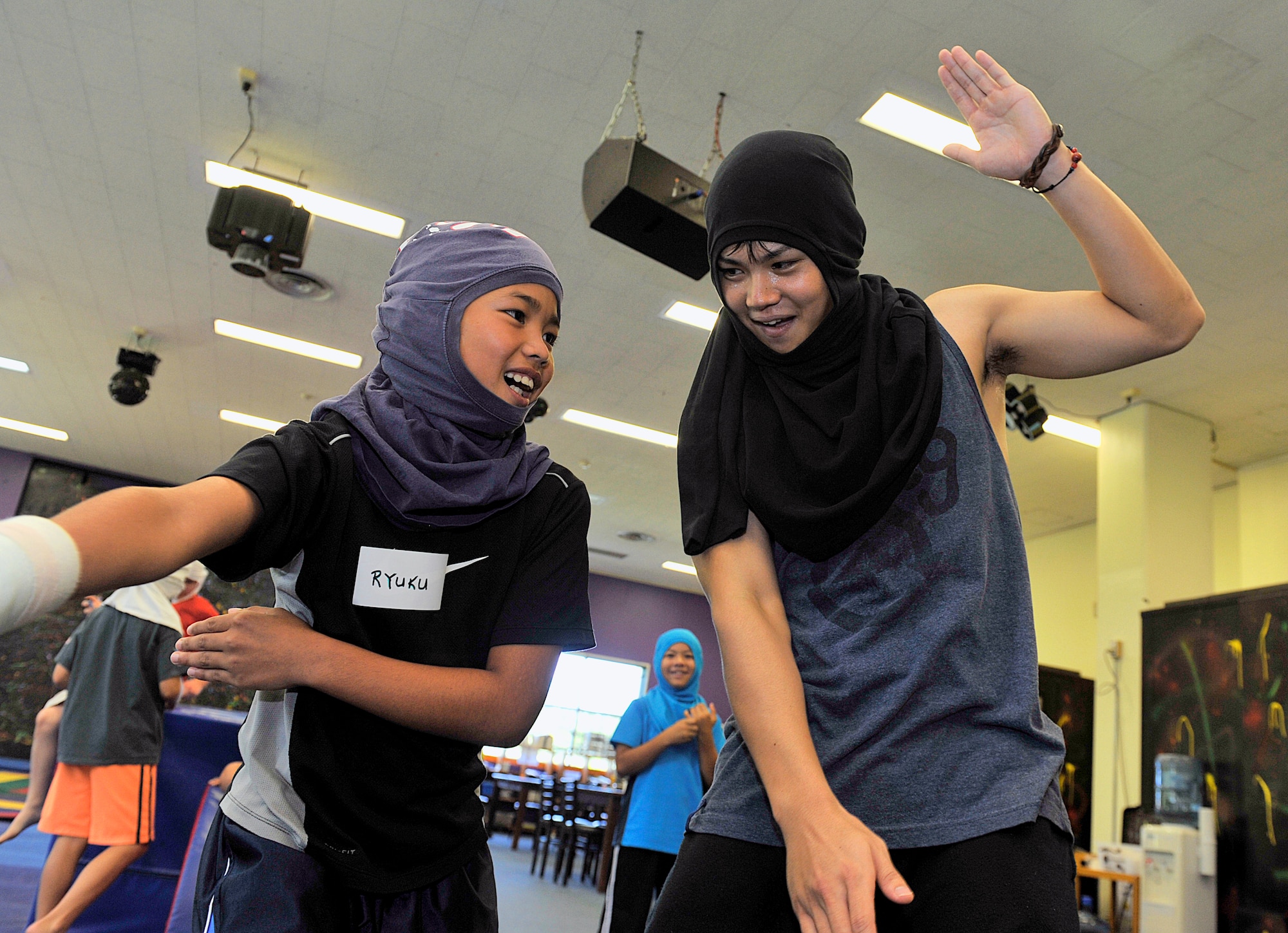 Ryuku Yogi (9) from Chatan Elementary School and Shota Kaneshiro, assistant from Chatan Lions Club, plays a ninja game at the Youth Center during a visit on Kadena Air Base, Japan, July 23, 2015. American and Japanese children ages 9-13 spent time together learning about each other's culture by playing games and having an American style lunch. (U.S. Air Force photo by Naoto Anazawa)