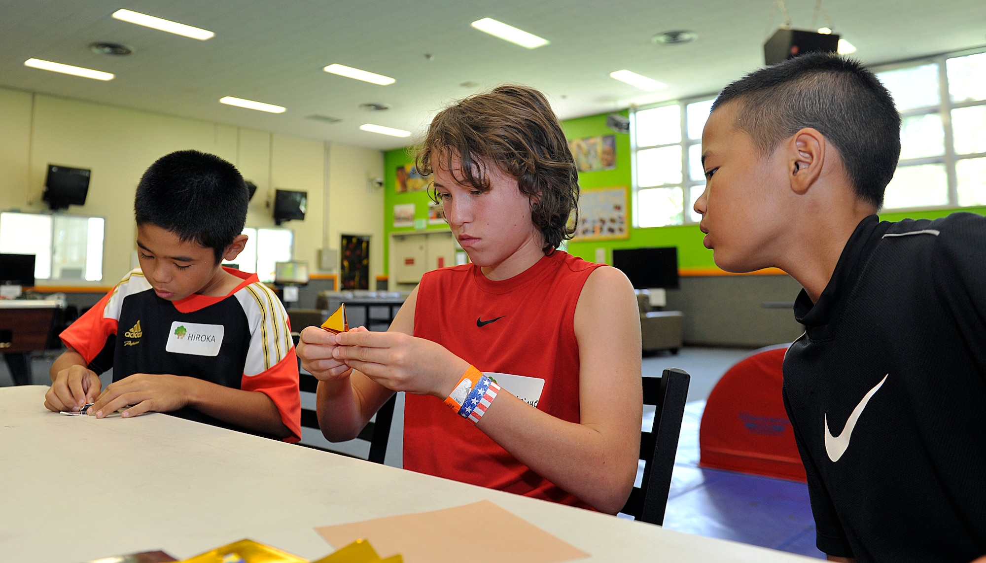 Ryuku Yogi (9) from Hamagawa Elementary School watches his partner Dominique Colon (13) make a Shuriken (ninja throwing star) with origami paper at the Youth Center during a visit on Kadena Air Base, Japan, July 23, 2015. A total of 14 children from Chatan Town elementary schools visited the Youth Center and had an opportunity to experience American culture and interact with American children their age. (U.S. Air Force photo by Naoto Anazawa)

