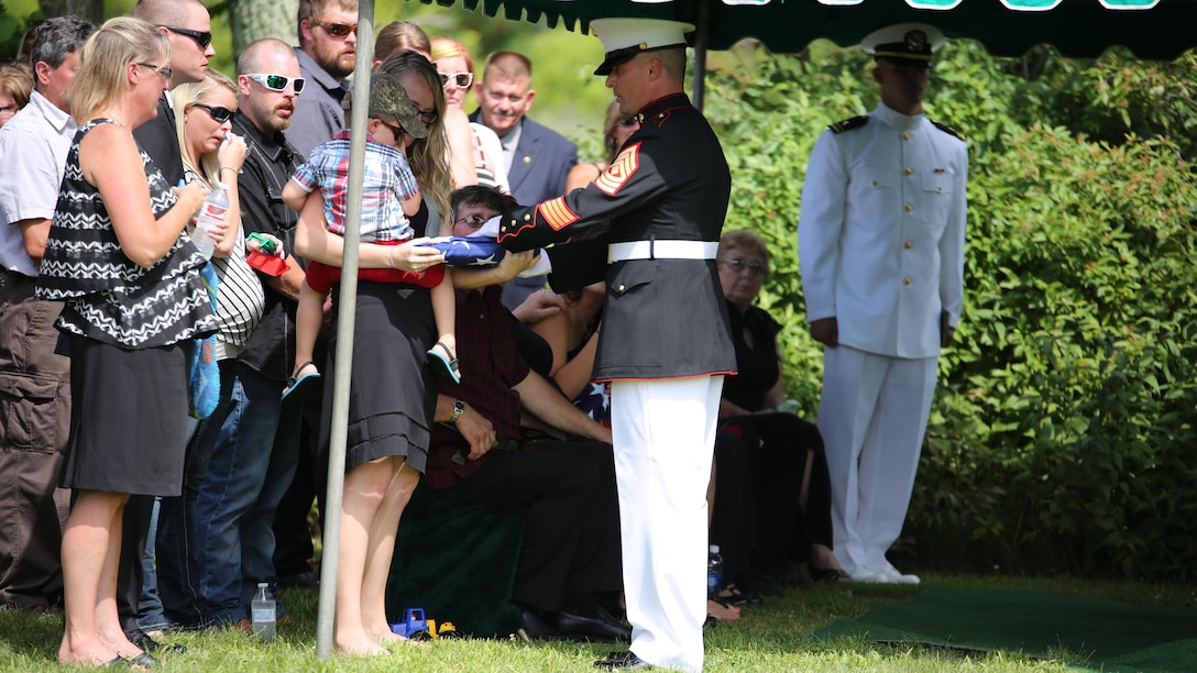 First Sgt. Timothy Dennison, the detachment first sergeant for Marine Wing Support Squadron 471, 4th Marine Aircraft Wing, presents a folded flag to the son of Sgt. Carson Holmquist, a motor transport maintenance chief with Battery M, 3rd Battalion, 14th Marine Regiment, 4th Marine Division, Marine Forces Reserve, during his funeral July 25, 2015 in Grantsburg, Wisconsin. Holmquist, along with three other Marines and a sailor, was killed in an attack at the Naval Operation Support Center and Marine Corps Reserve Center in Chattanooga, Tennessee July 16, 2015. Marines, family, friends and the community of Grantsburg gathered to honor the memory and sacrifice of Holmquist and his fallen brothers-in-arms. 