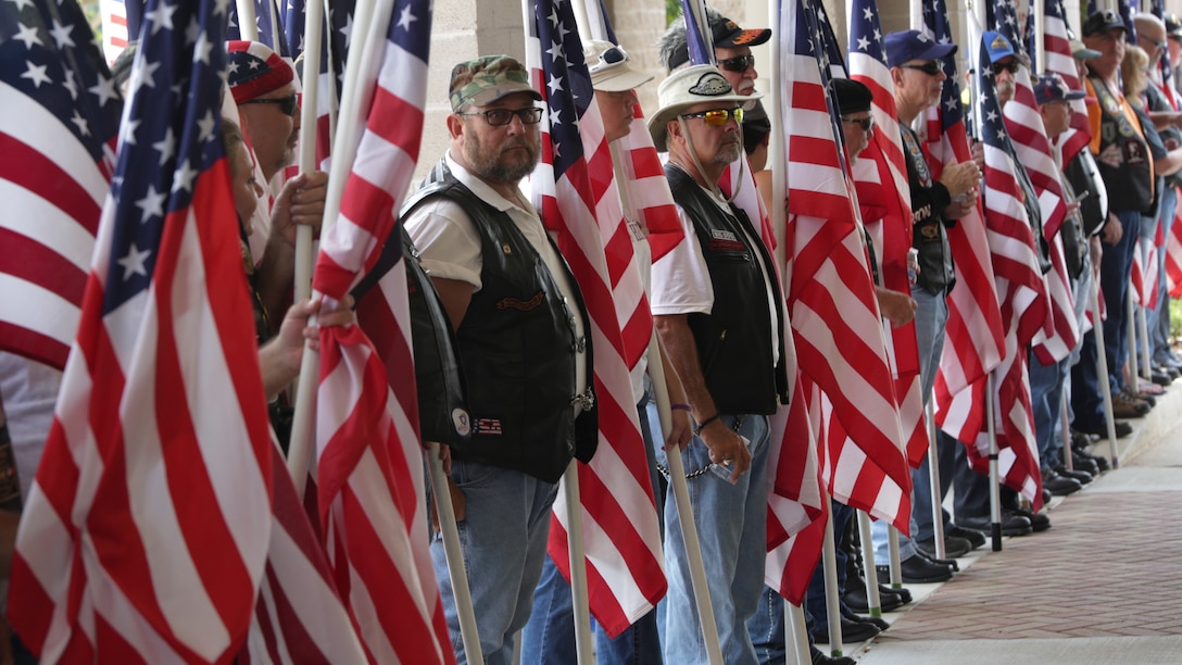 Service members, veterans and civilians hold American flags and stand outside the First Baptist Church of Woodstock entrance, waiting for Lance Cpl. Squire “Skip” Wells’ casket to arrive July 26, 2015 in Woodstock, Georgia. Wells was one of five service members killed during a shooting at the Naval Operational Support Center and Marine Corps Reserve Center on July 16, 2015. More than a thousand people attended the funeral service to pay their respects and show support to Wells and his family.