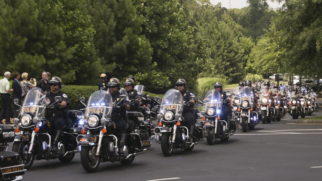 Hundreds of police officers drive cars and motorcycles to escort the hearse of Lance Cpl. Squire “Skip” Wells and his family at the First Baptist Church of Woodstock July 26, 2015 in Woodstock, Georgia. Wells was one of five service members killed during a shooting at the Naval Operational Support Center and Marine Corps Reserve Center on July 16, 2015. Hundreds of people were present at the service showing their respect and support for Wells, his family and friends.