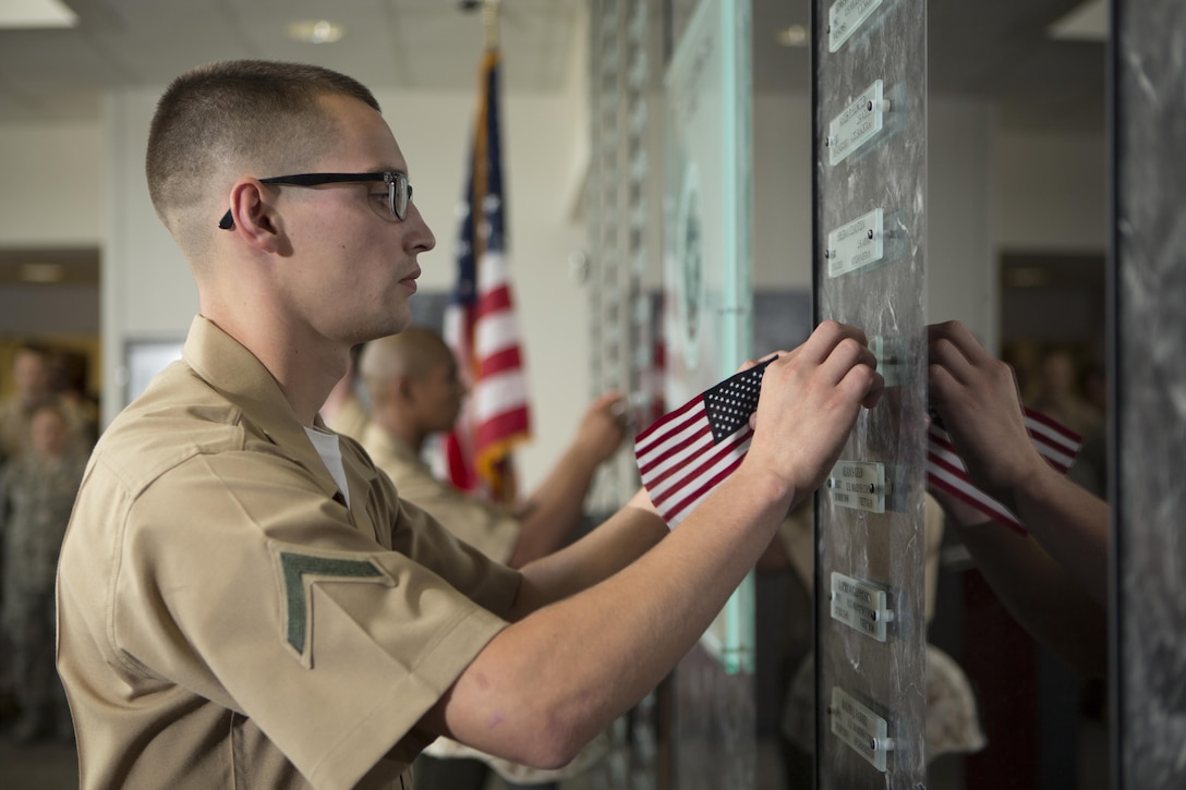 U.S. Marine Corps Pfc. Andrew Piehler, a Marine awaiting training, unveils a name placard during a memorial service and induction ceremony in the Hall of Heroes at the Defense Information School on Fort George G. Meade, Md., July 27, 2015. The ceremony was in honor of U.S. Marine Corps Cpl. Sara A. Medina and Lance Cpl. Jacob A. Hug, combat photographers who were killed during earthquake relief operations in Nepal, May 12, 2015. (DoD photo by Shane Keller/Released)