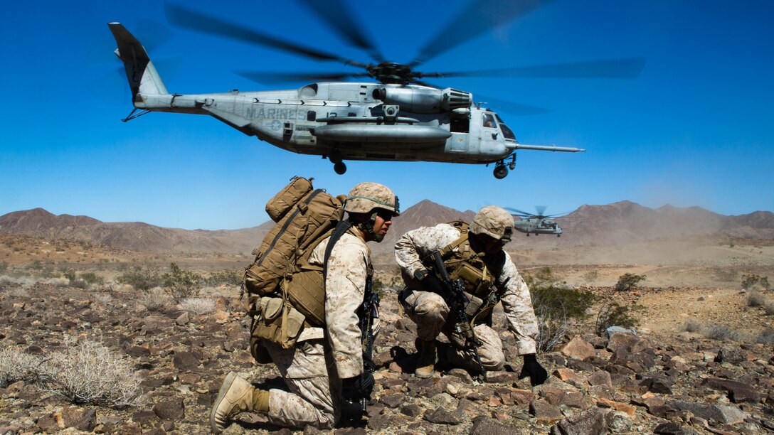 Petty Officer 3rd Class Steven Martinez, left, a corpsman, and Staff Sgt. Joseph Quintanilla, a platoon sergeant, both with Company B, 1st Battalion, 3rd Marine Regiment, brace as a CH-53E Super Stallion with Marine Heavy Helicopter Squadron 366 takes off after inserting the company into a landing zone aboard Marine Corps Air Ground Combat Center Twentynine Palms, Calif., July 26. The Marines were inserted to conduct ground air integration training.